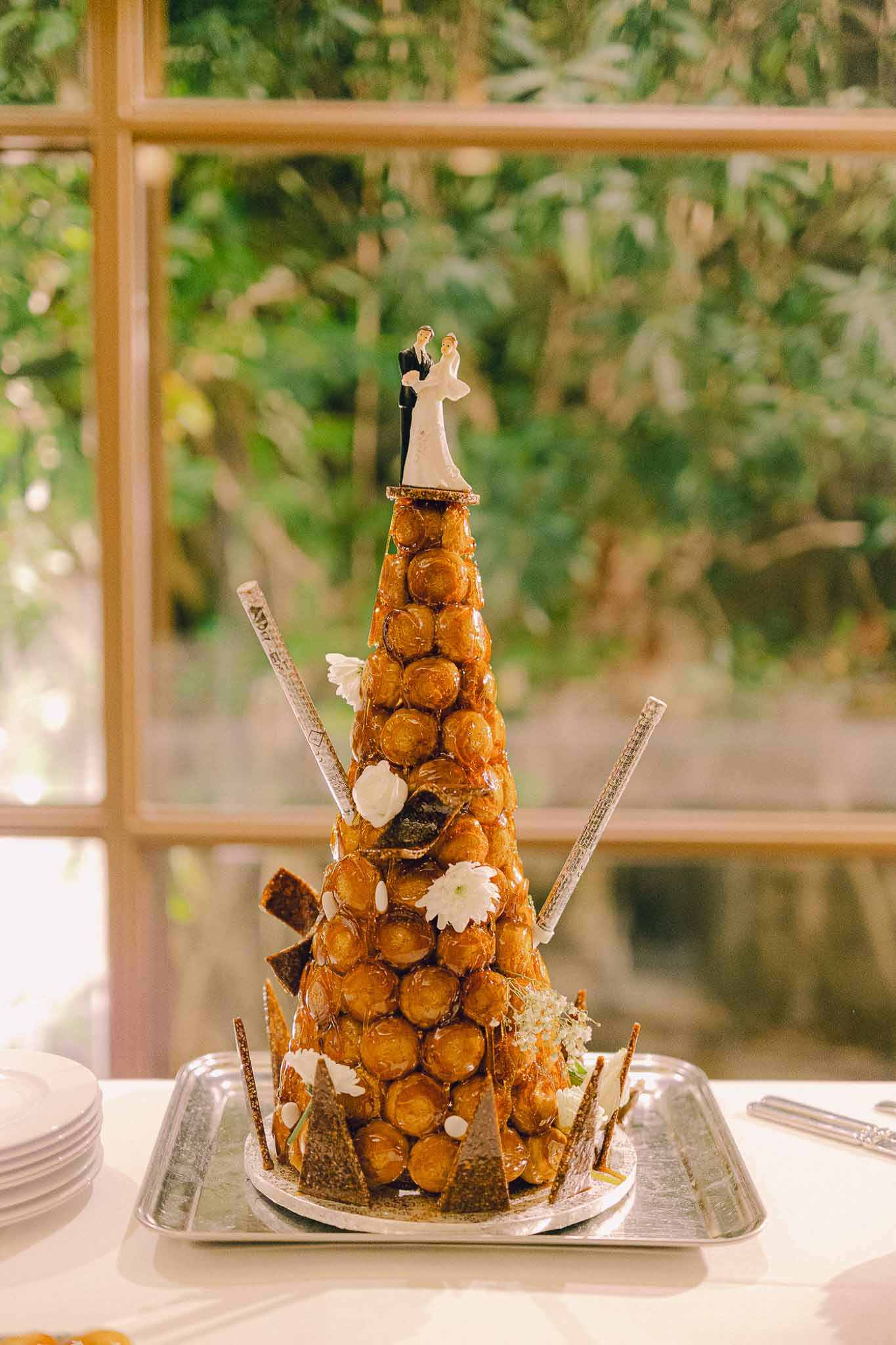 French croquembouche wedding cake with caramelized cream puffs and sugar flowers on reception table