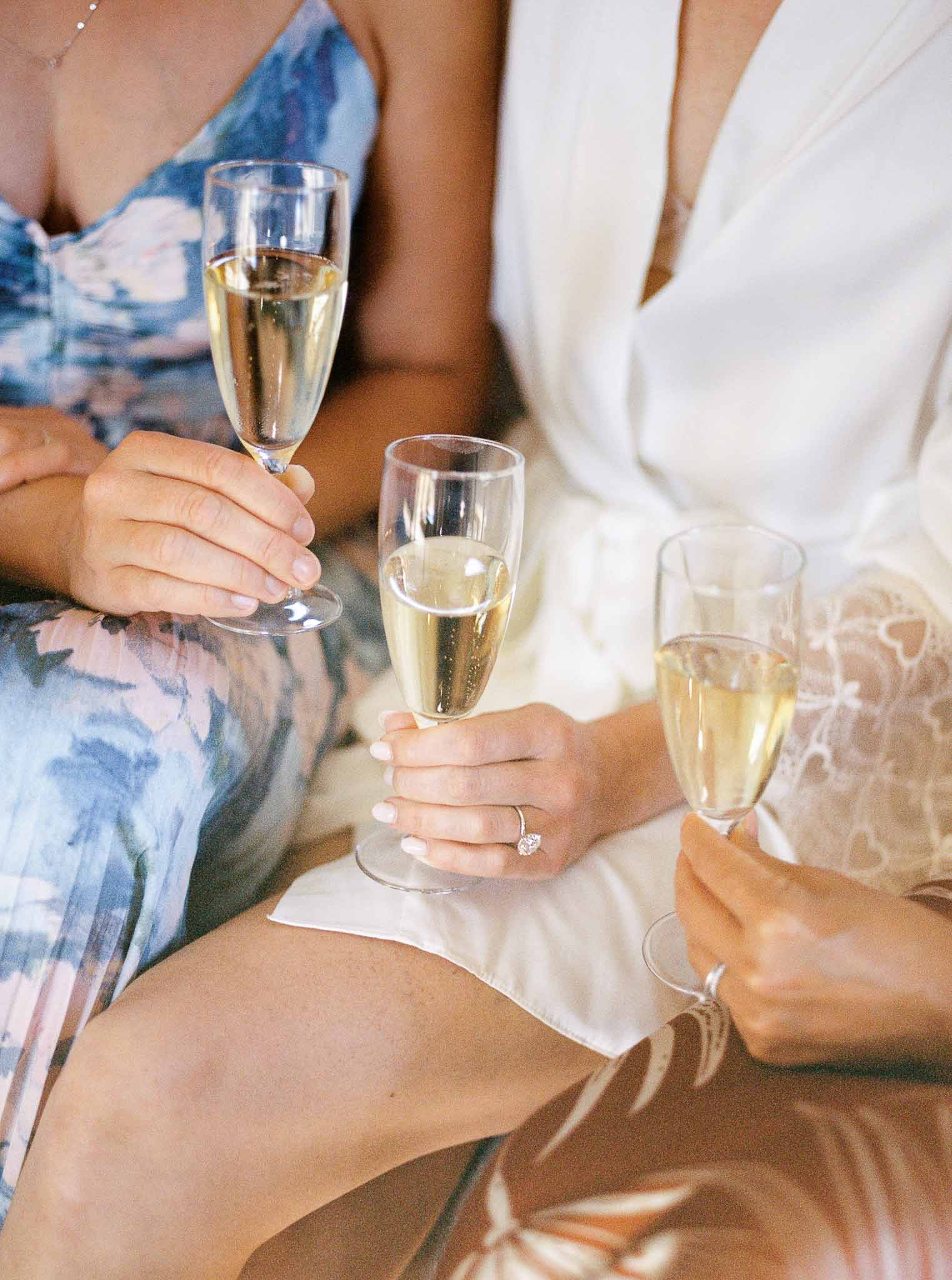 Guests toasting with champagne flutes during wedding reception, bride in ivory lace dress with diamond ring