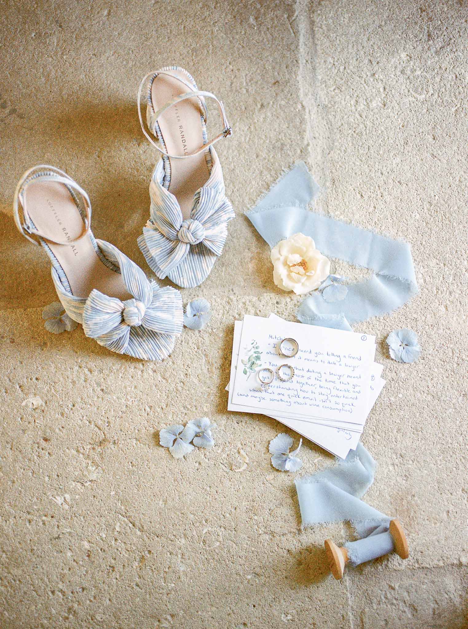 Bridal accessories and wedding rings arranged in flat lay on stone surface