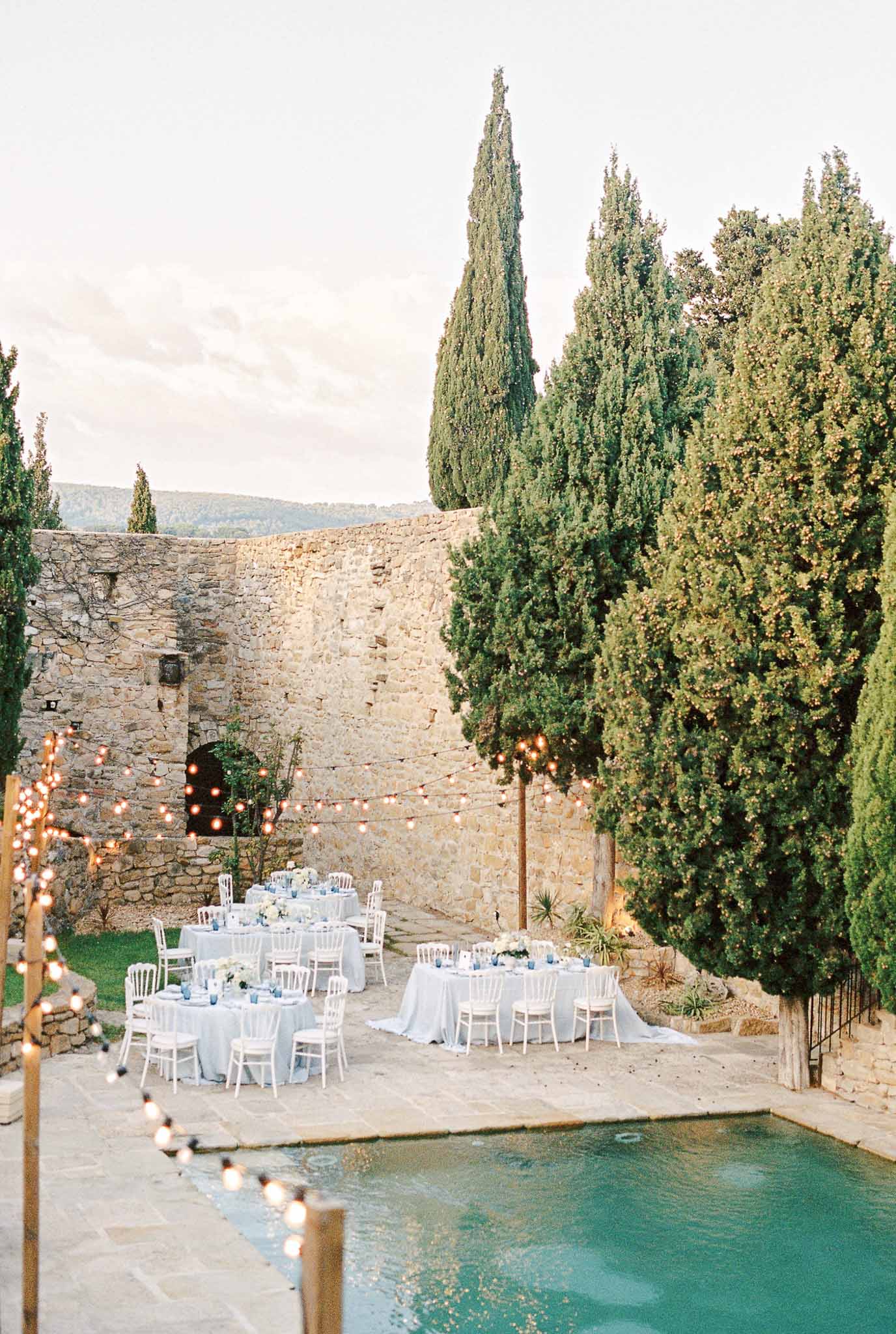 Historic stone courtyard reception setup with pool and cypress trees at Mediterranean wedding venue