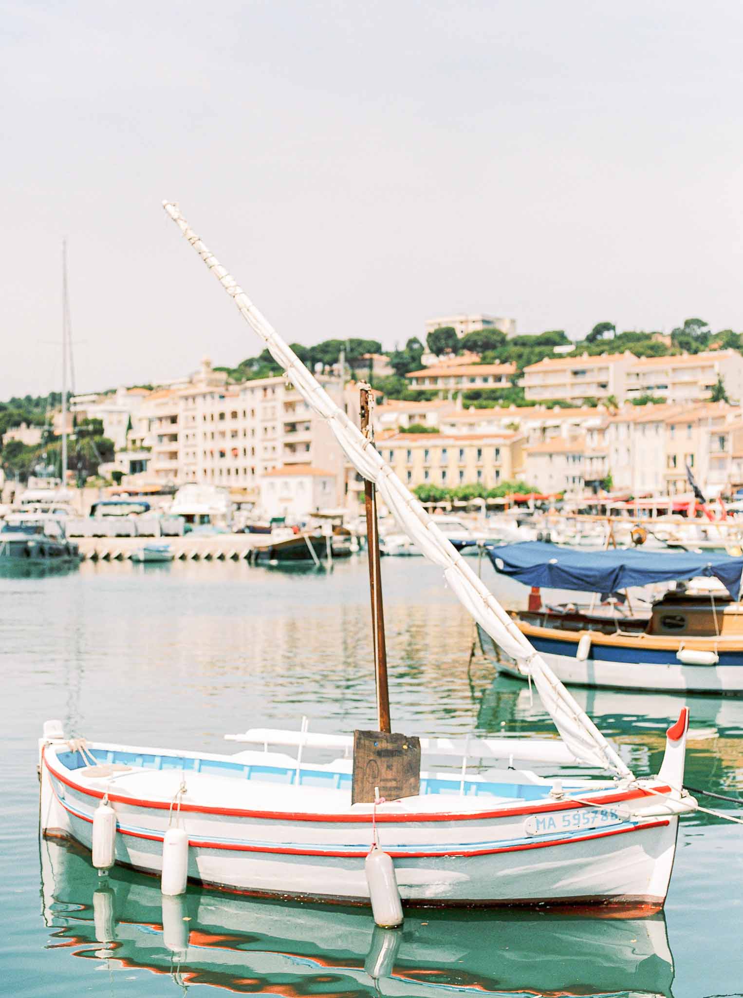 Traditional fishing boat moored in Mediterranean harbor with hillside village backdrop for coastal wedding venue