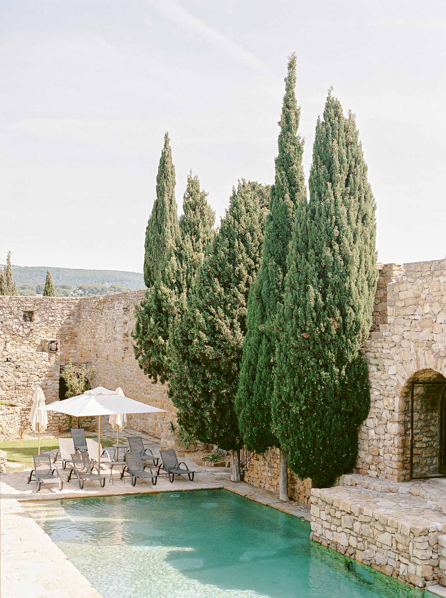 Poolside courtyard with stone architecture and cypress trees at Mediterranean wedding venue