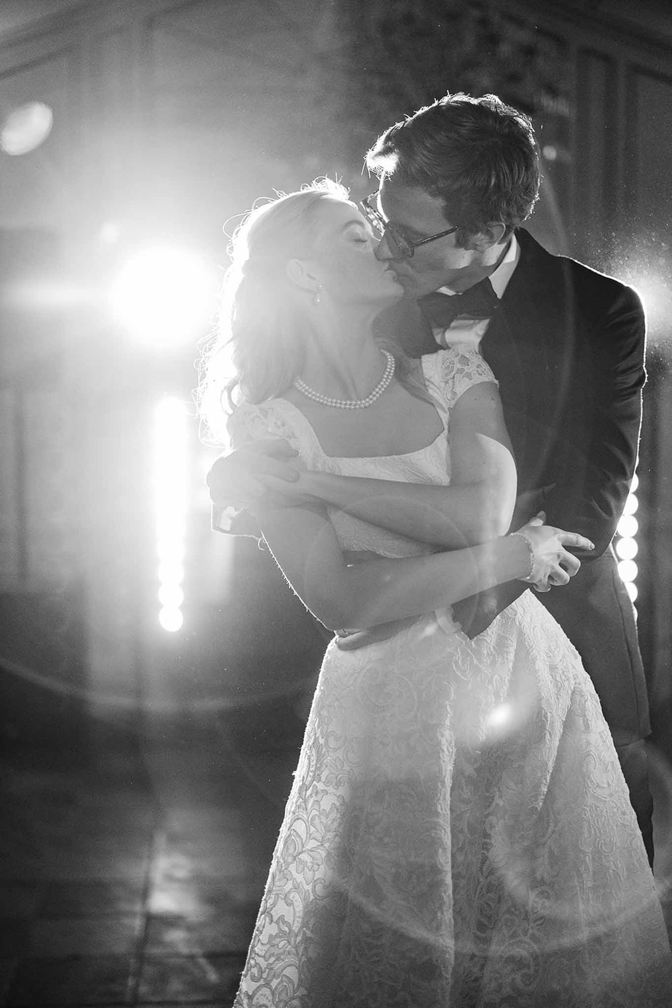 Bride and groom sharing first dance kiss at indoor wedding reception