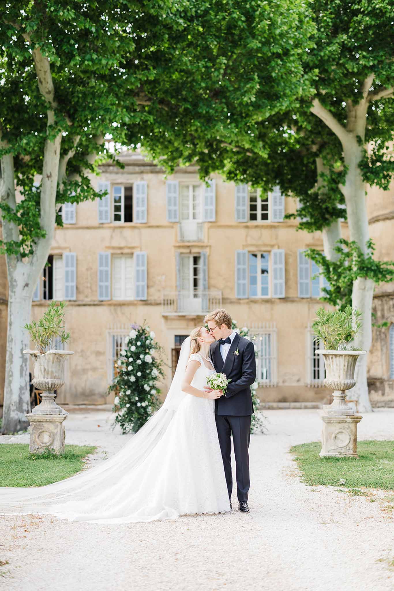 Bride and groom kissing in formal courtyard with classical French architecture