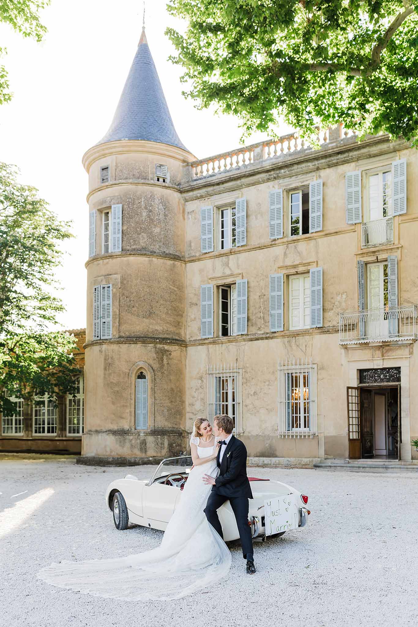 Bride and groom portrait with vintage car at château courtyard