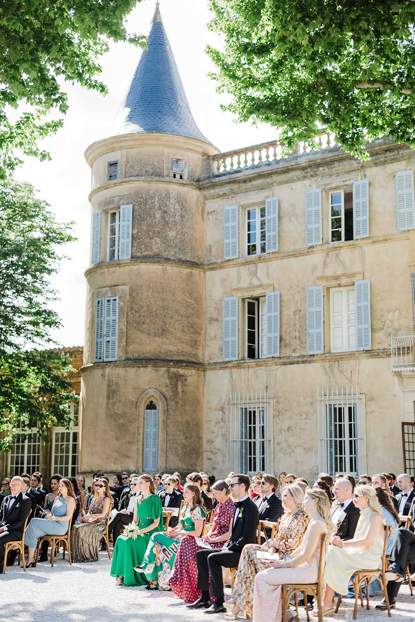 Outdoor wedding ceremony with guests seated in château courtyard with historic stone architecture