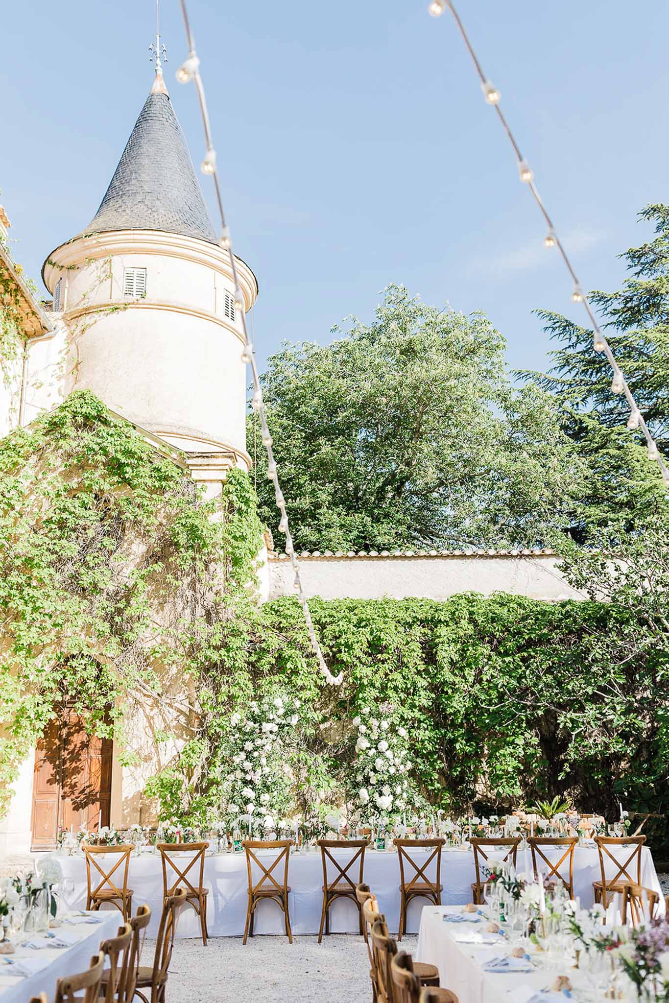 Outdoor reception setup in château courtyard with ivy-covered stone walls and conical tower