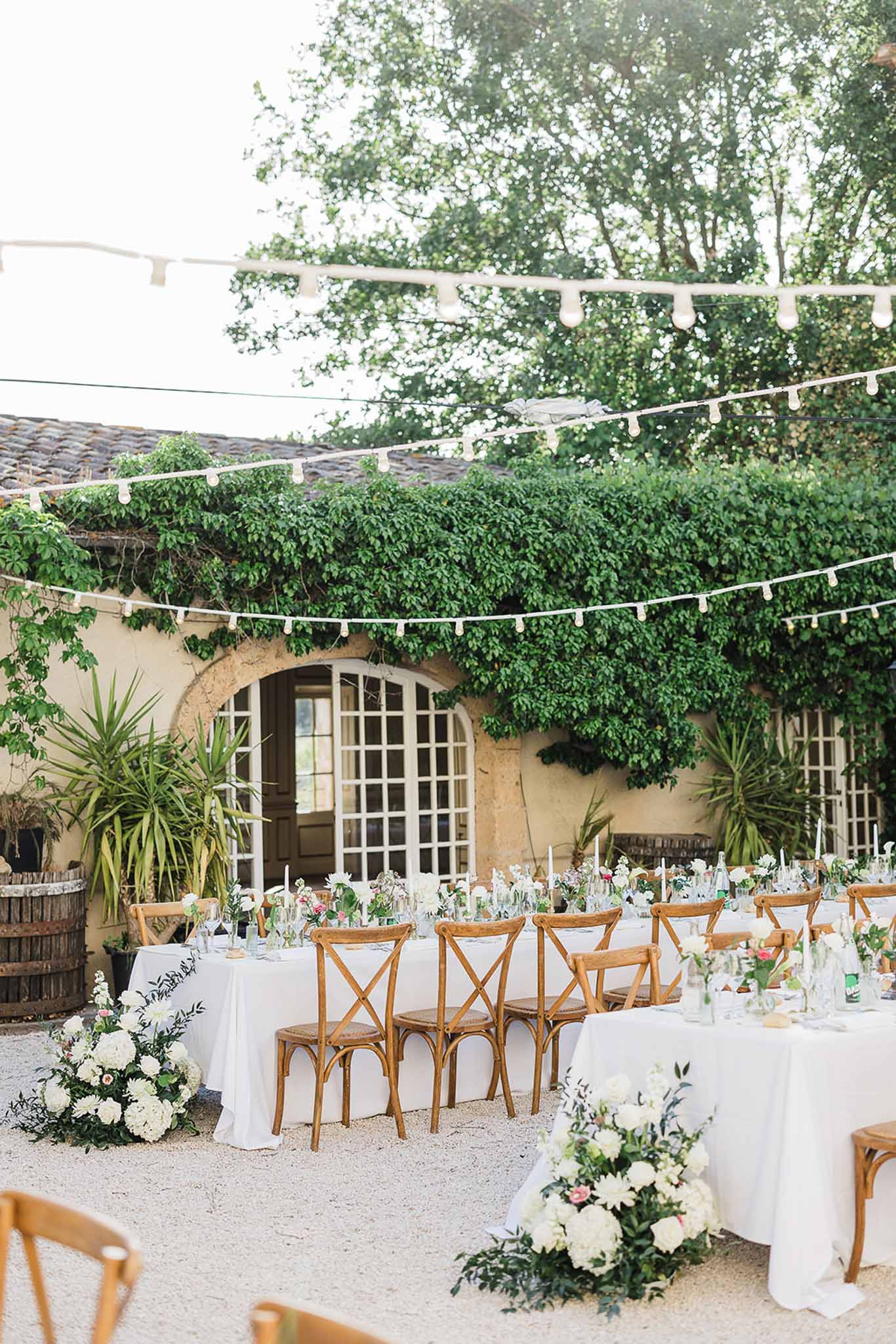 Mediterranean courtyard reception setup with stone architecture and bistro lighting