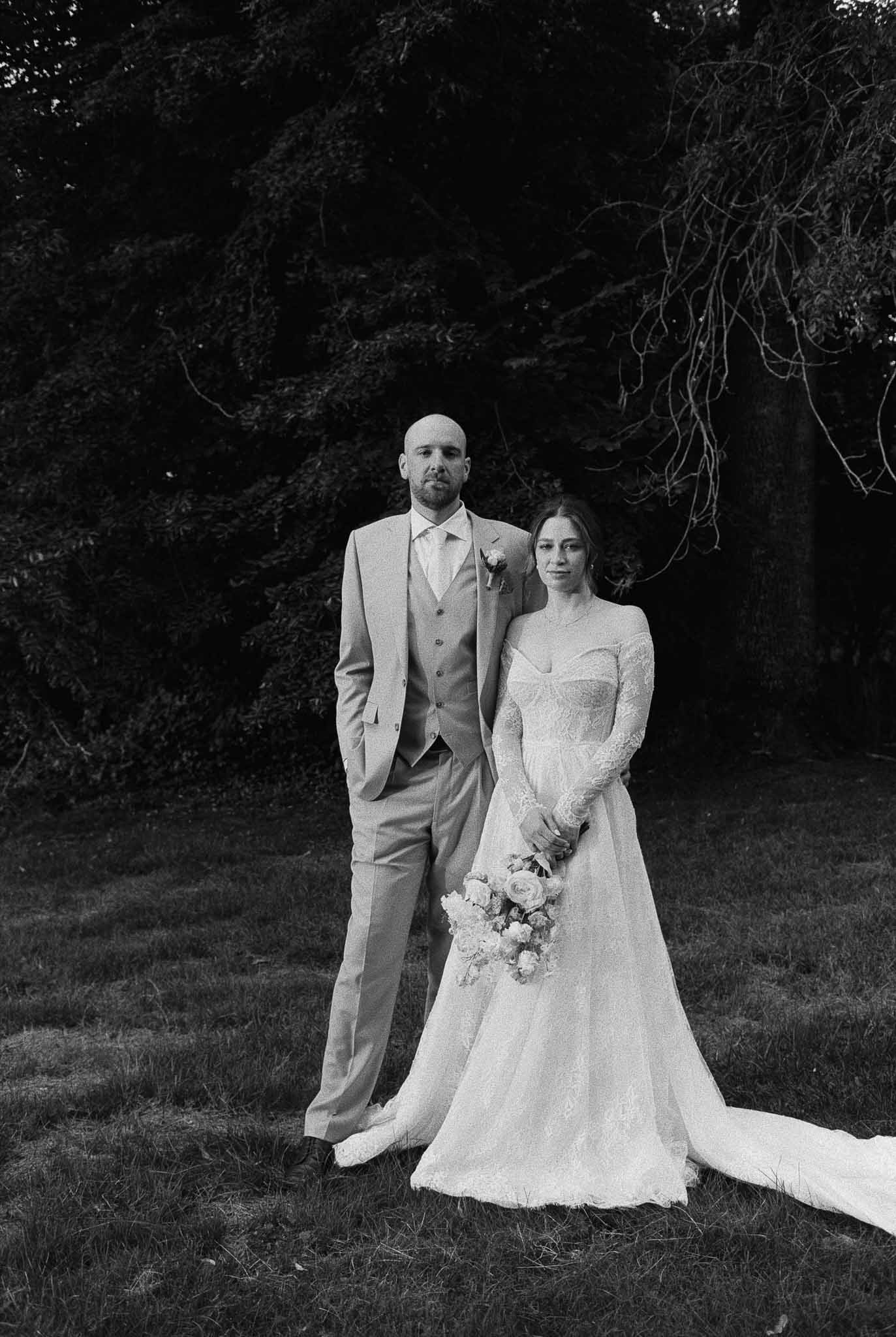 Black and white bride and groom formal portrait outdoors against foliage backdrop