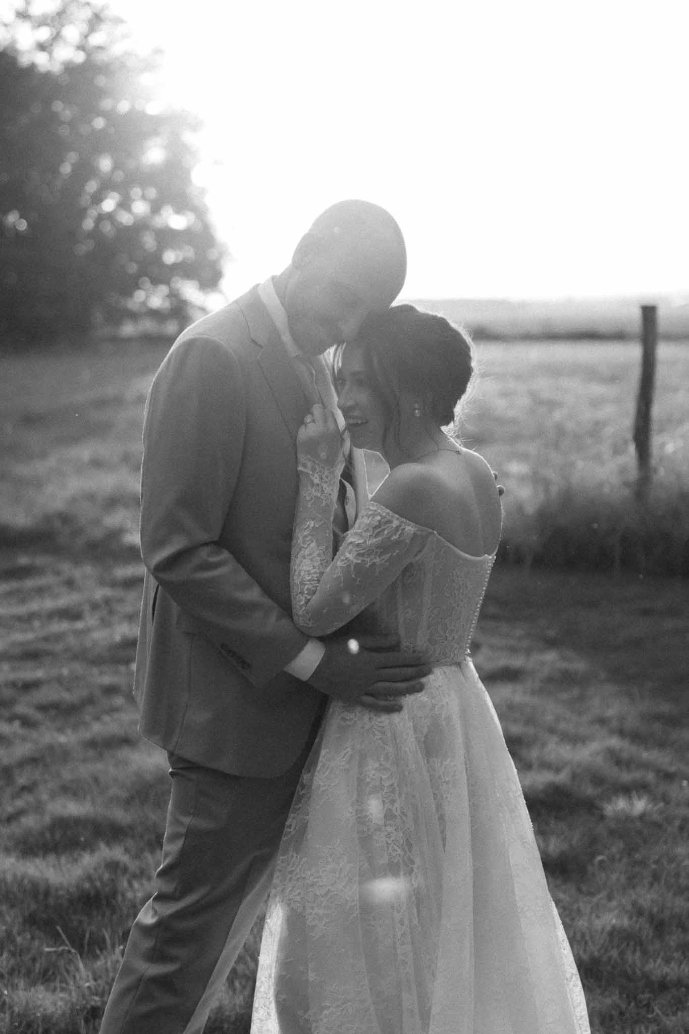 Bride and groom embracing in countryside field portrait at rural wedding venue
