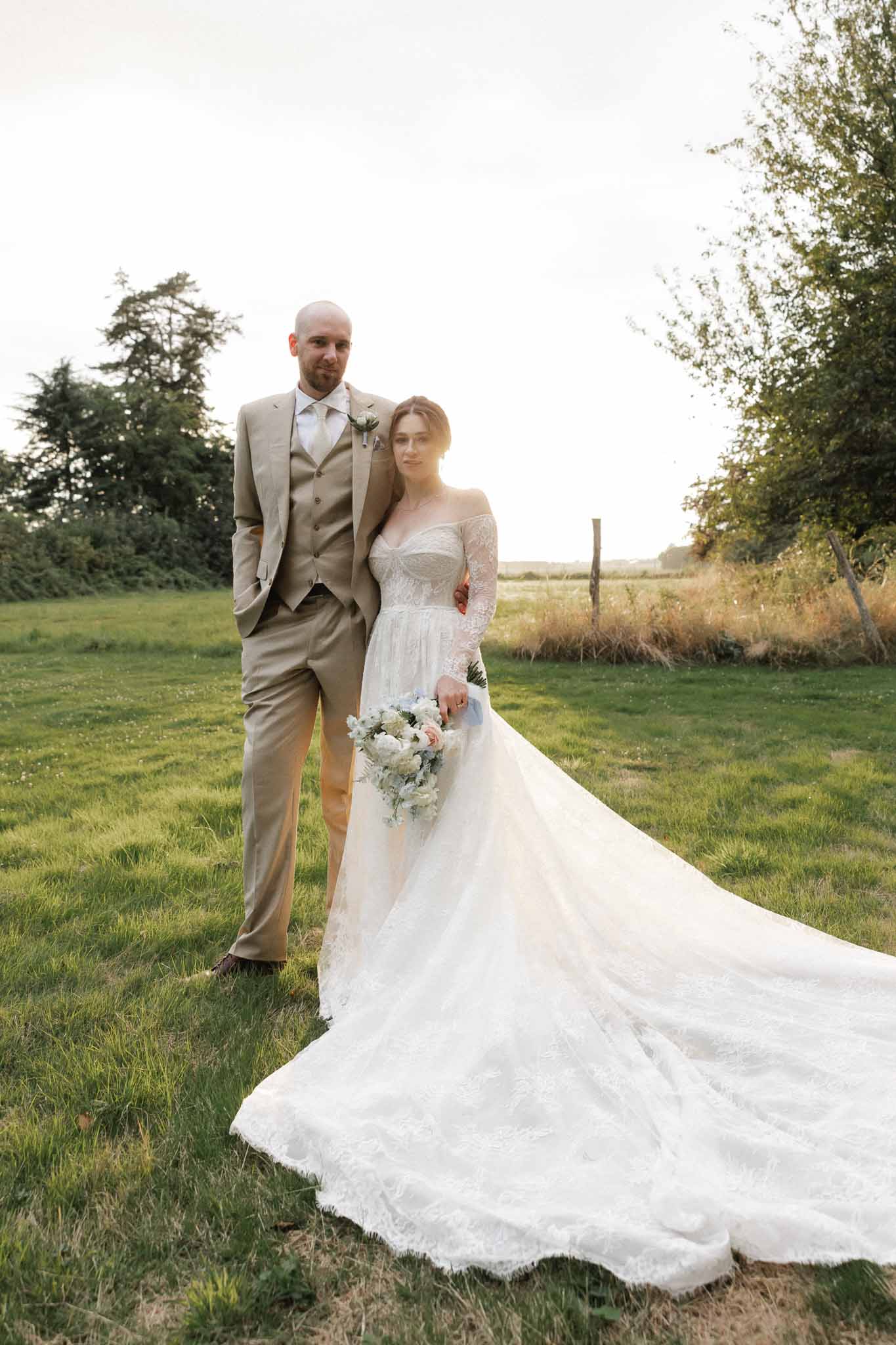 Bride and groom formal portrait in countryside field with mature trees and agricultural landscape