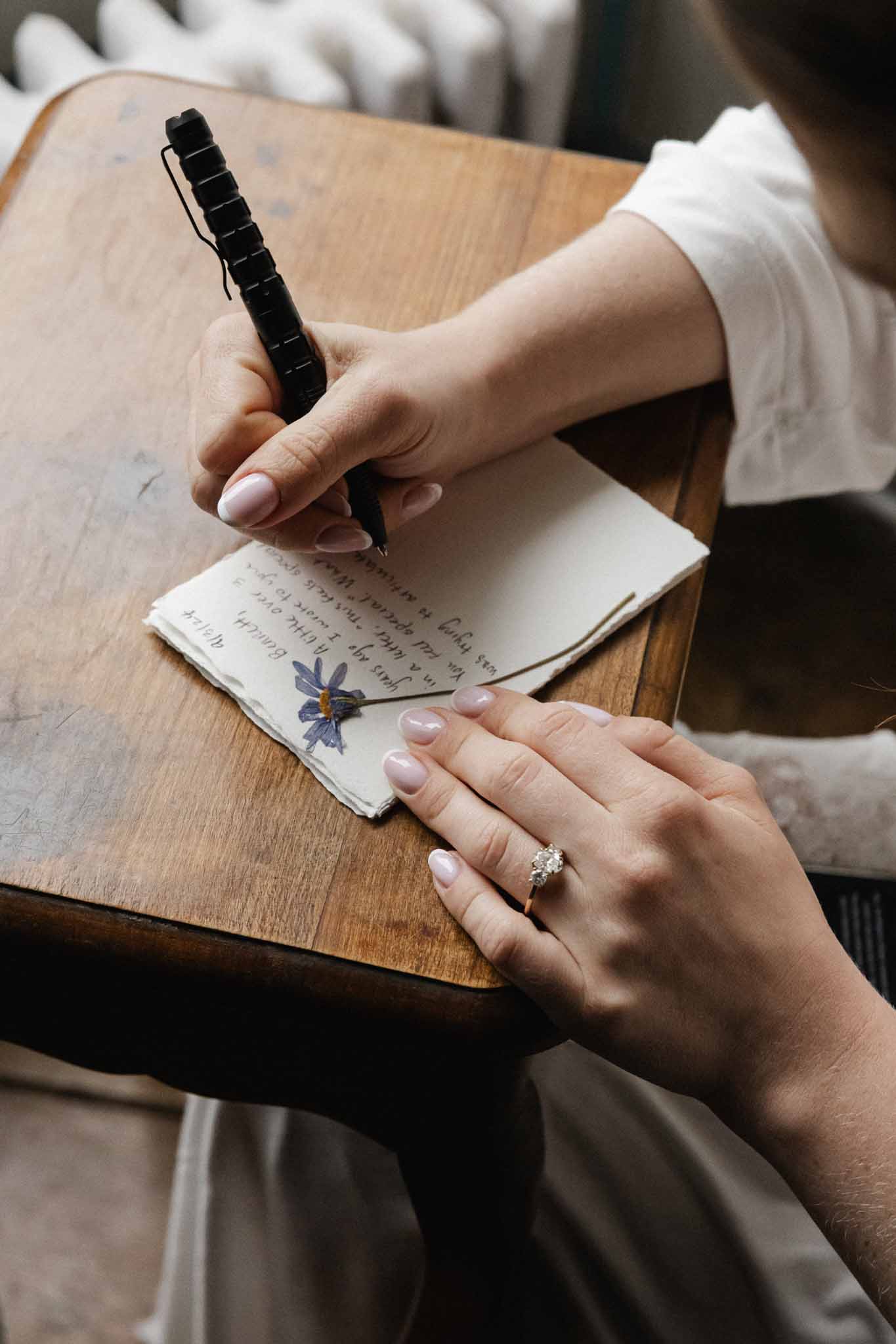 Bride signing guest book with hand-painted blue flower cover at wedding reception