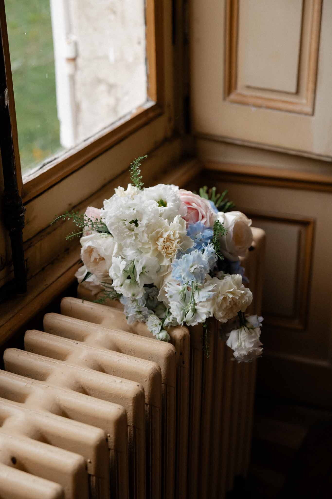 Bridal bouquet with white hydrangeas and roses on wooden staircase at country manor venue