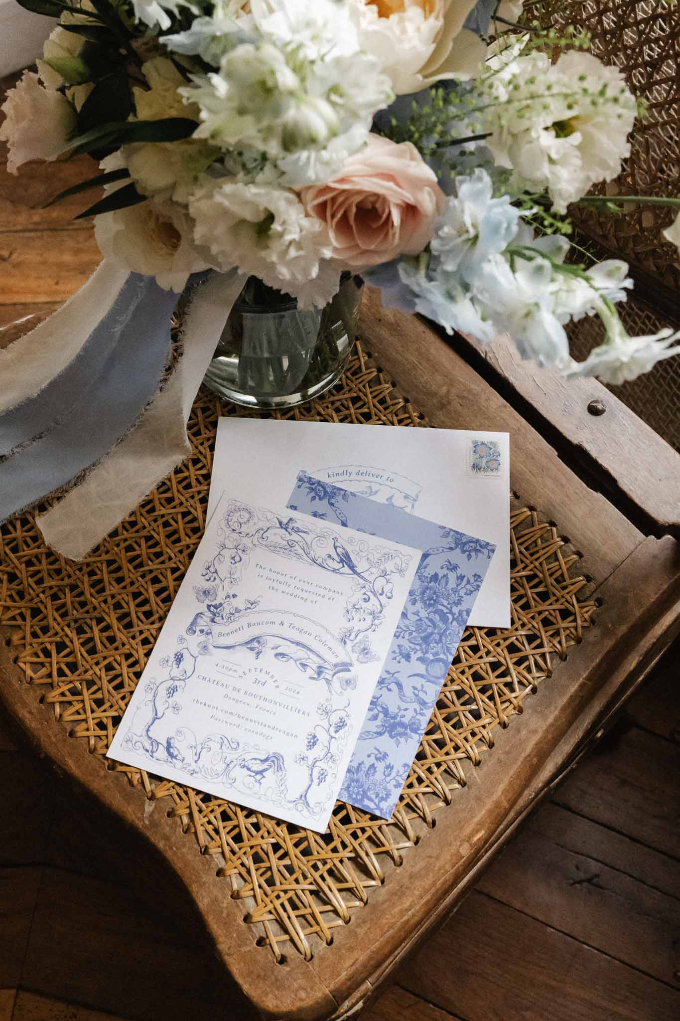 Wedding invitation suite with blue toile pattern and bridal bouquet arranged on wooden tray