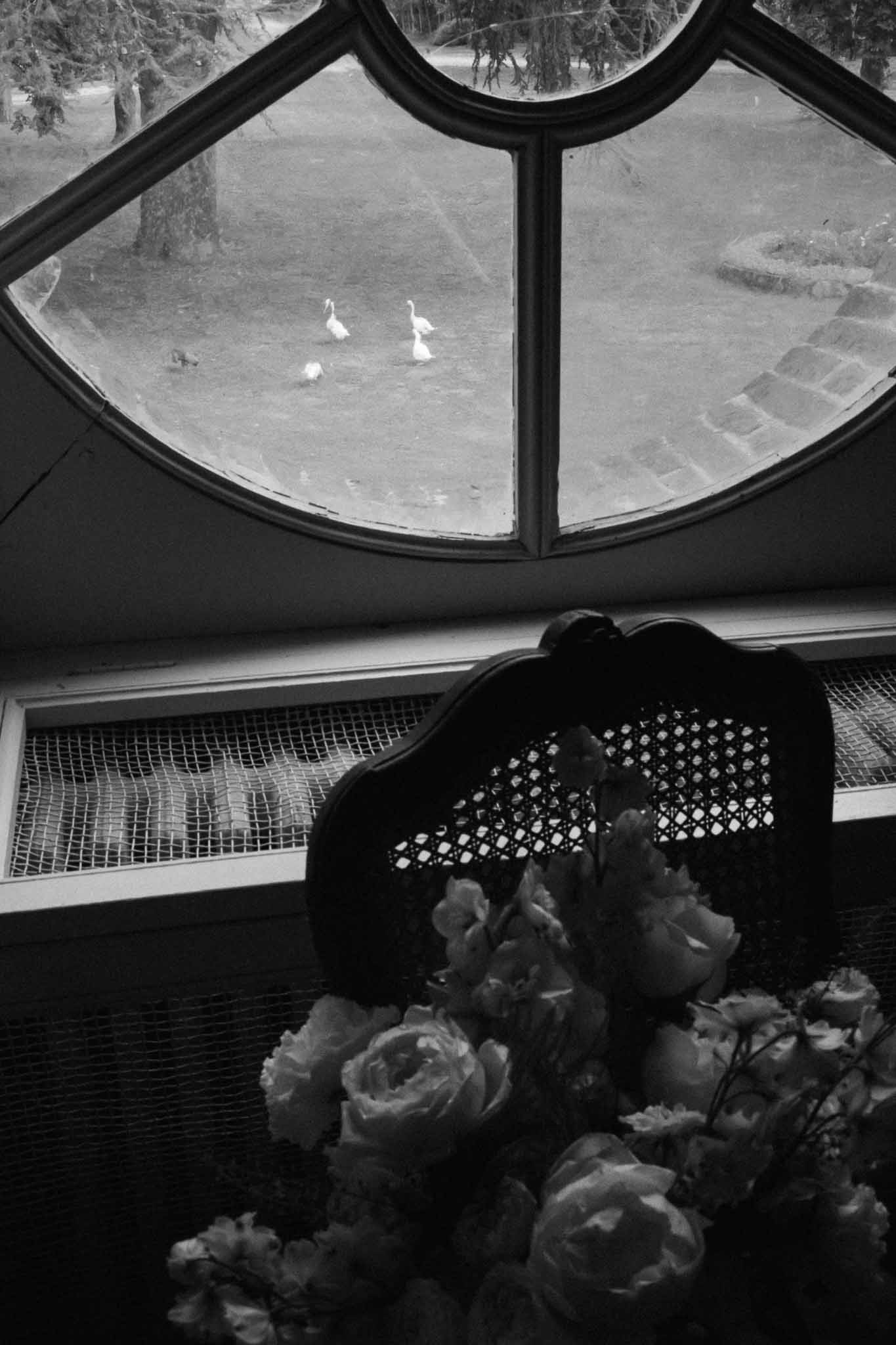 Bride holding bouquet looking through window at indoor wedding venue