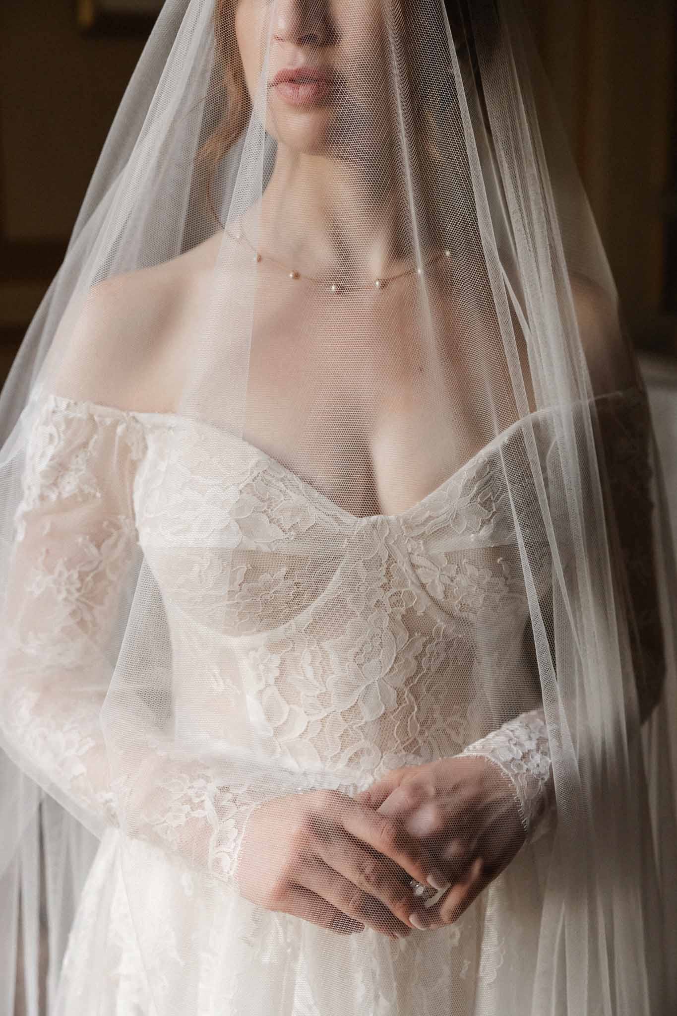 Close-up bridal portrait with ivory lace gown and tulle veil at wedding venue
