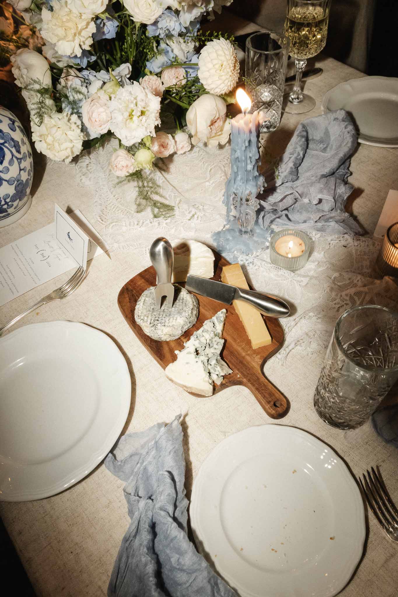 Overhead view of elegant reception table setting with floral centerpiece and cheese course at wedding venue