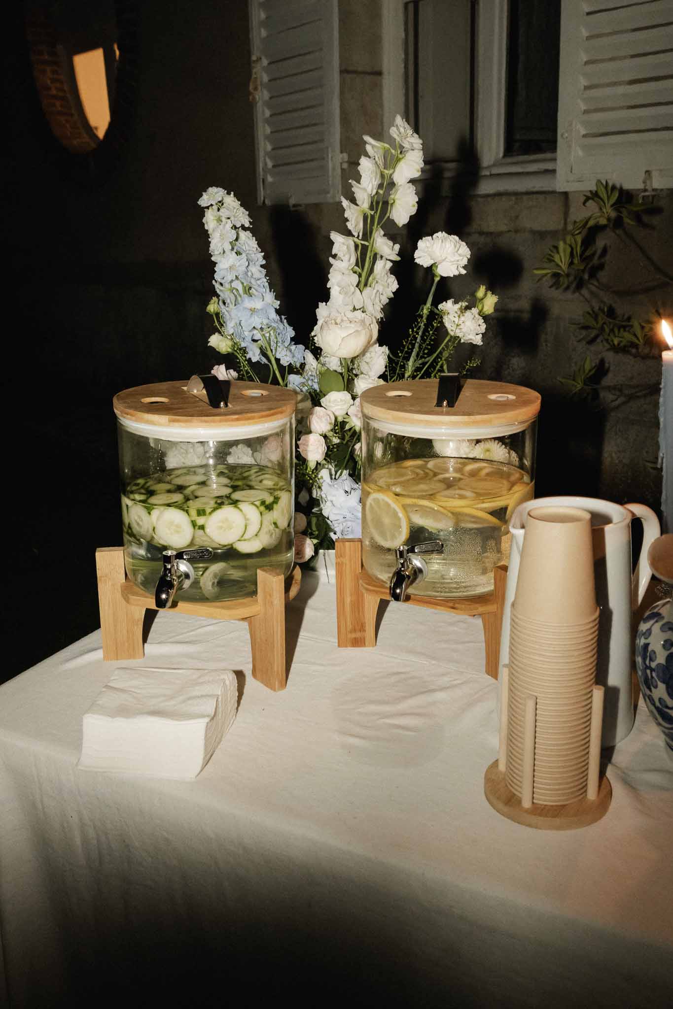 Beverage station with infused water dispensers and white floral arrangement at wedding reception