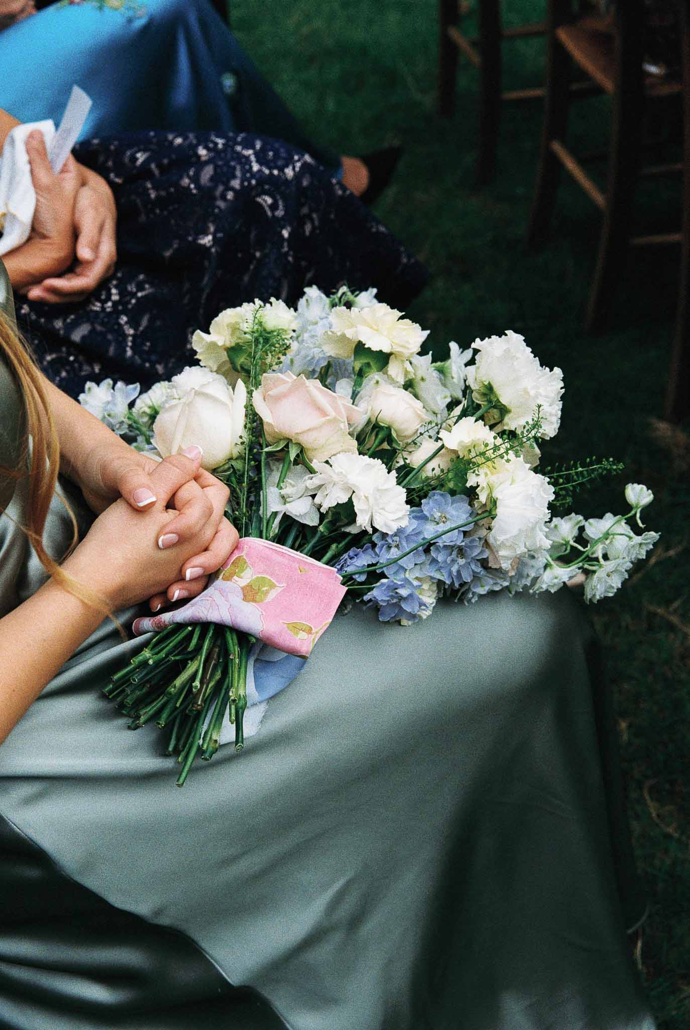 Bride holding ivory and blush bridal bouquet during outdoor garden ceremony