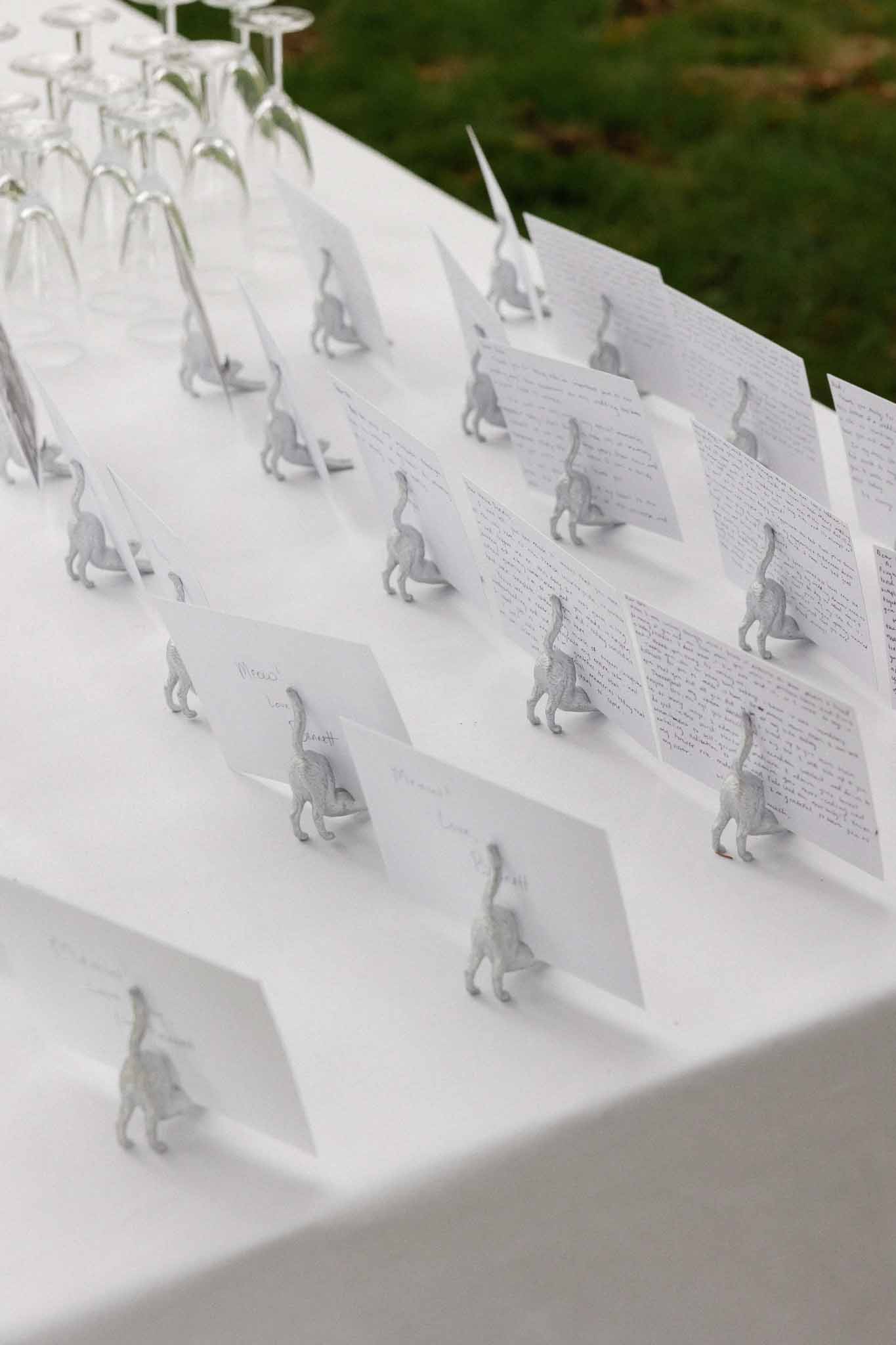 Place cards with silver horse figurines on white reception table linens