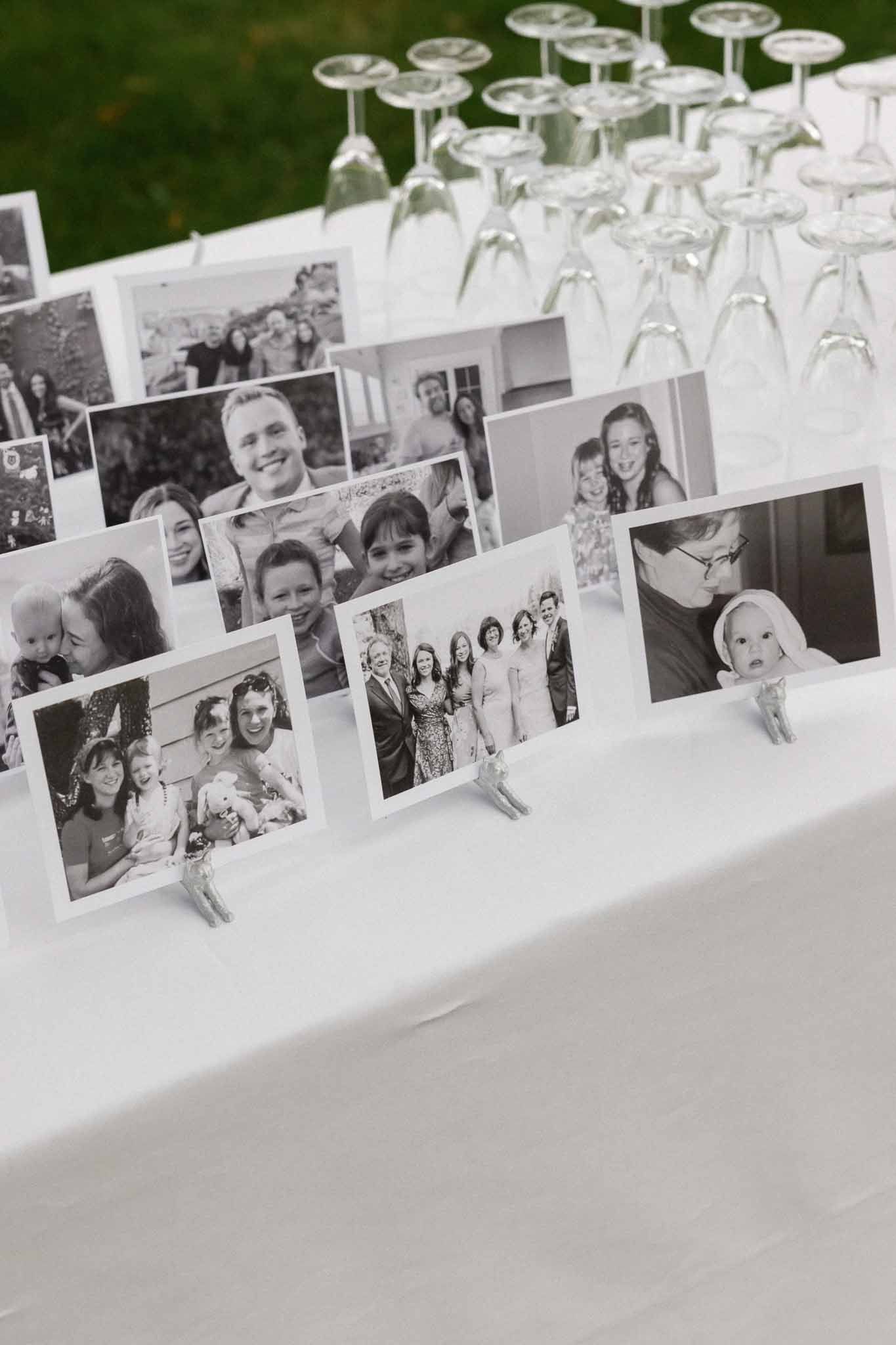 Family photo display with champagne glasses on reception table at outdoor wedding venue