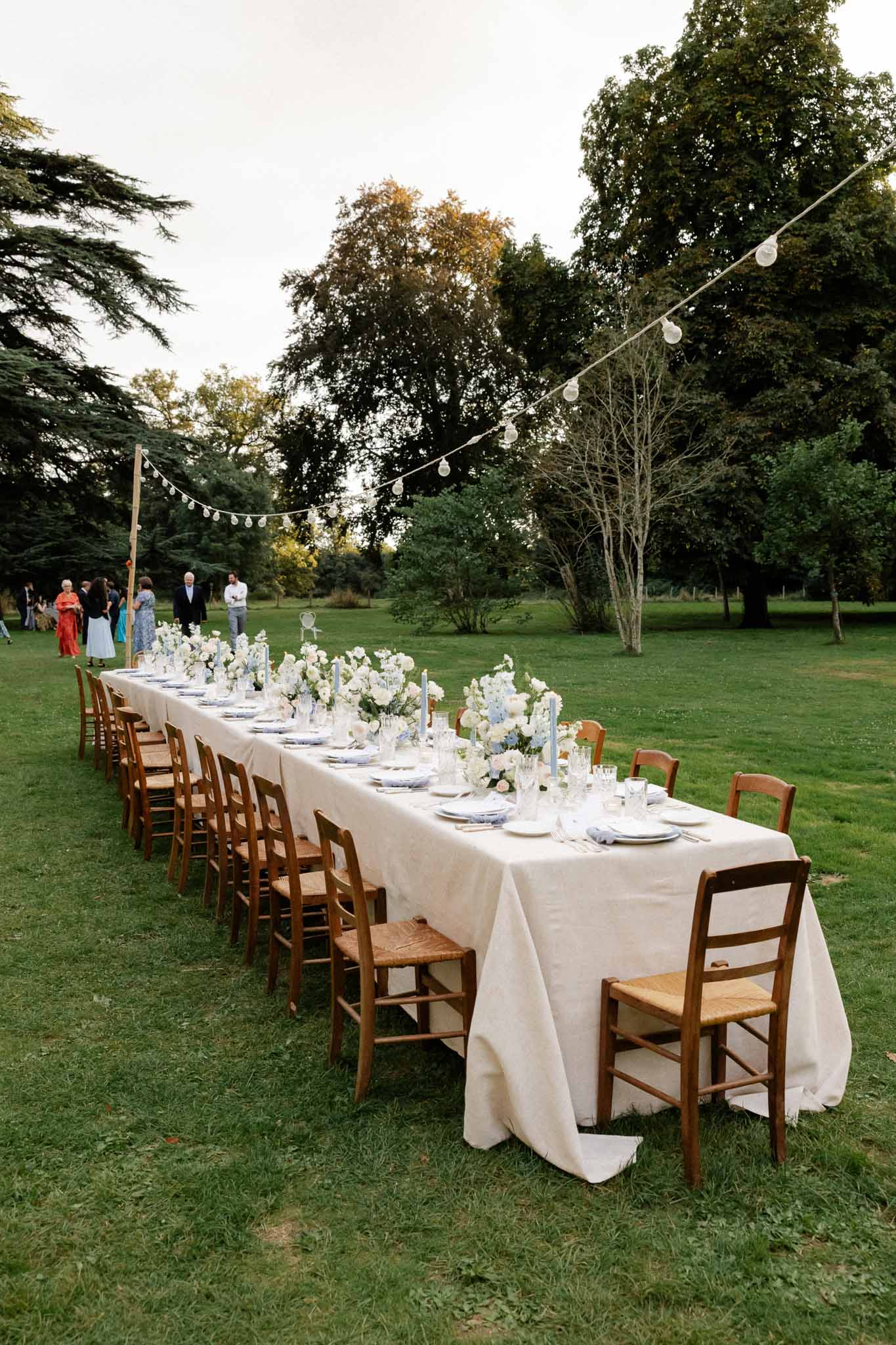 Reception dinner table with white linens and floral centerpieces set in garden estate grounds