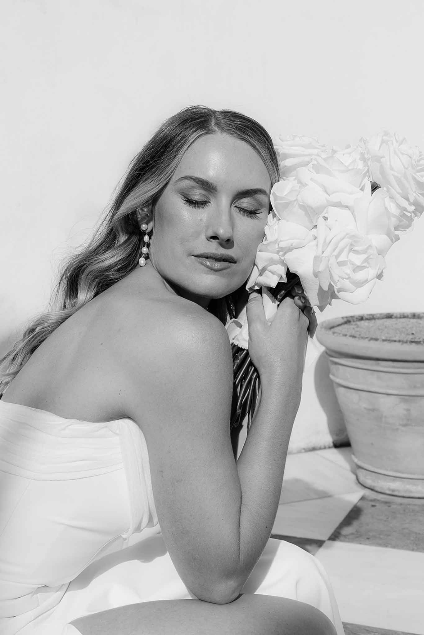 Black and white bridal portrait with bride holding white peony bouquet in close-up composition
