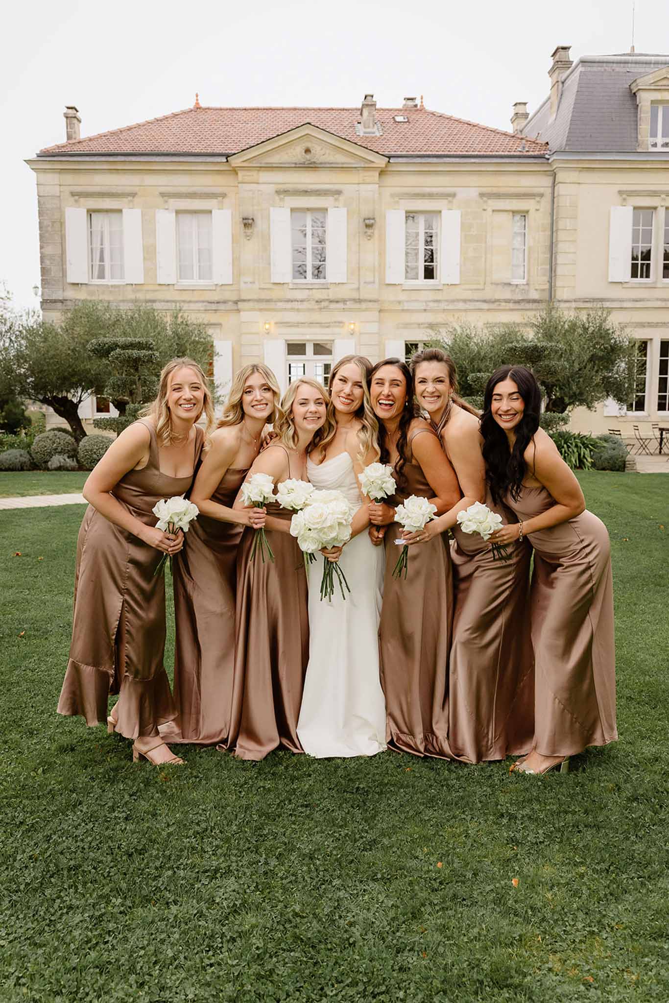 Bridal party portrait with bride and bridesmaids in front of neoclassical stone mansion