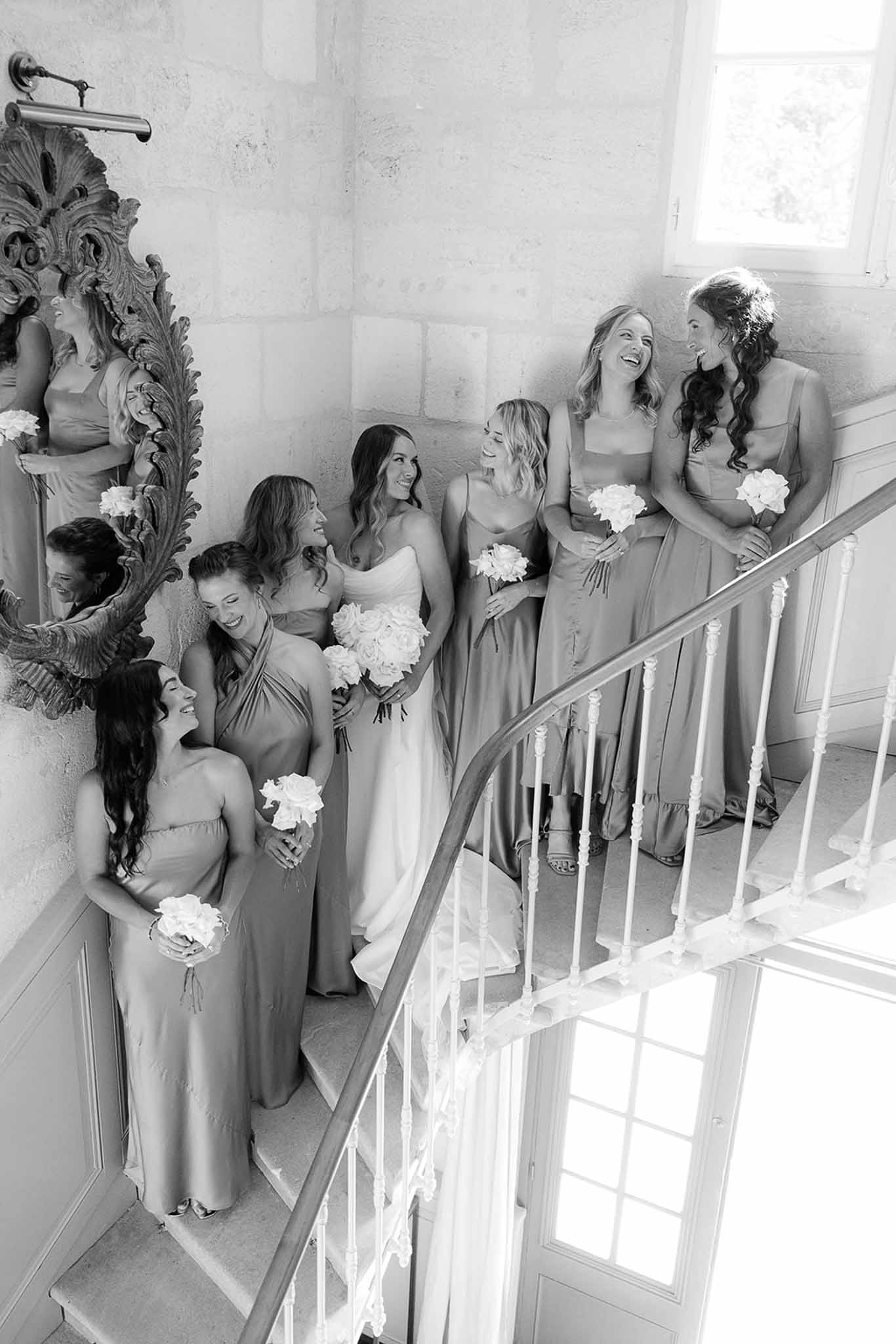 Bridesmaids with white peony bouquets on elegant staircase in classical interior setting