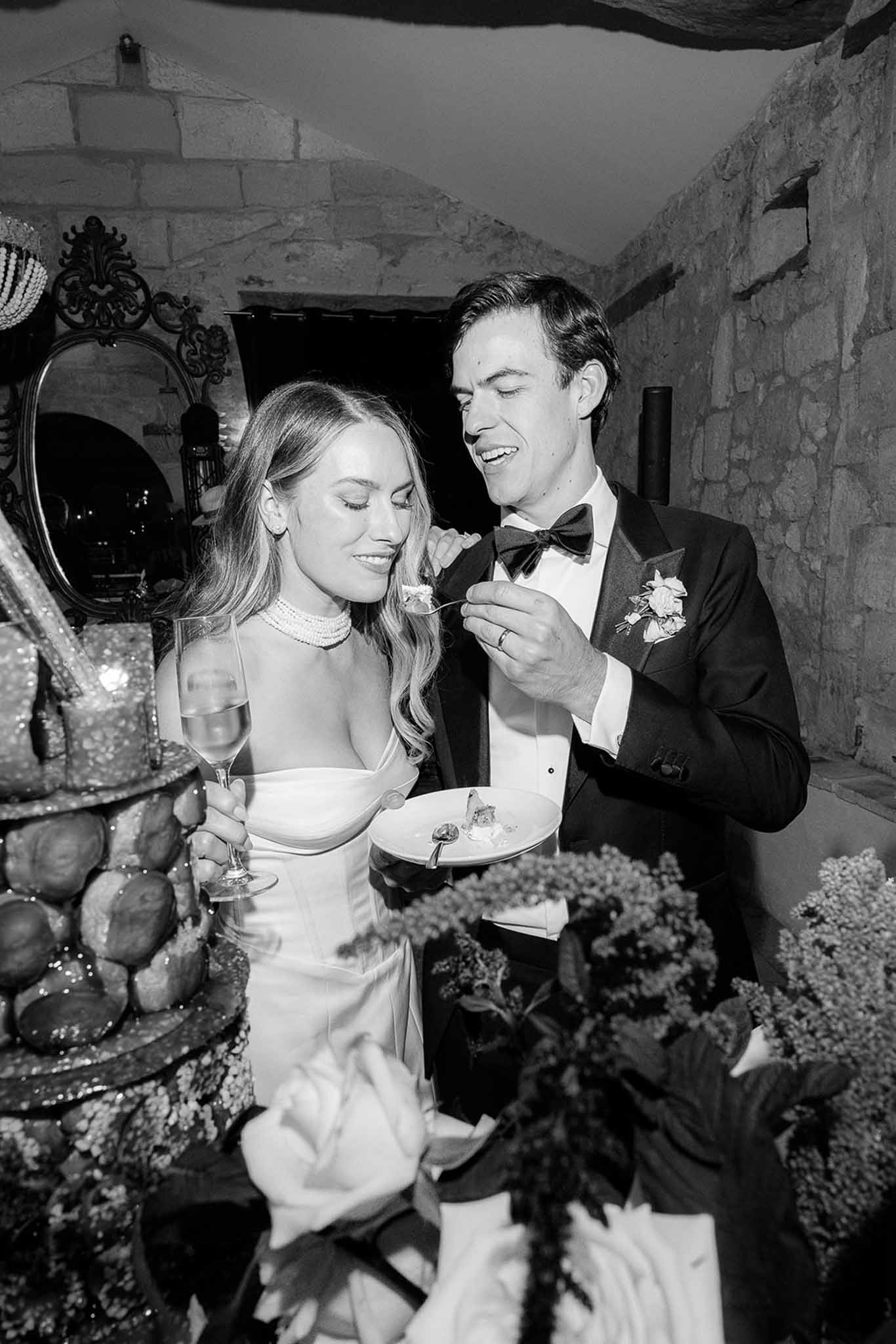 Couple sharing wedding cake during reception in rustic stone-walled venue