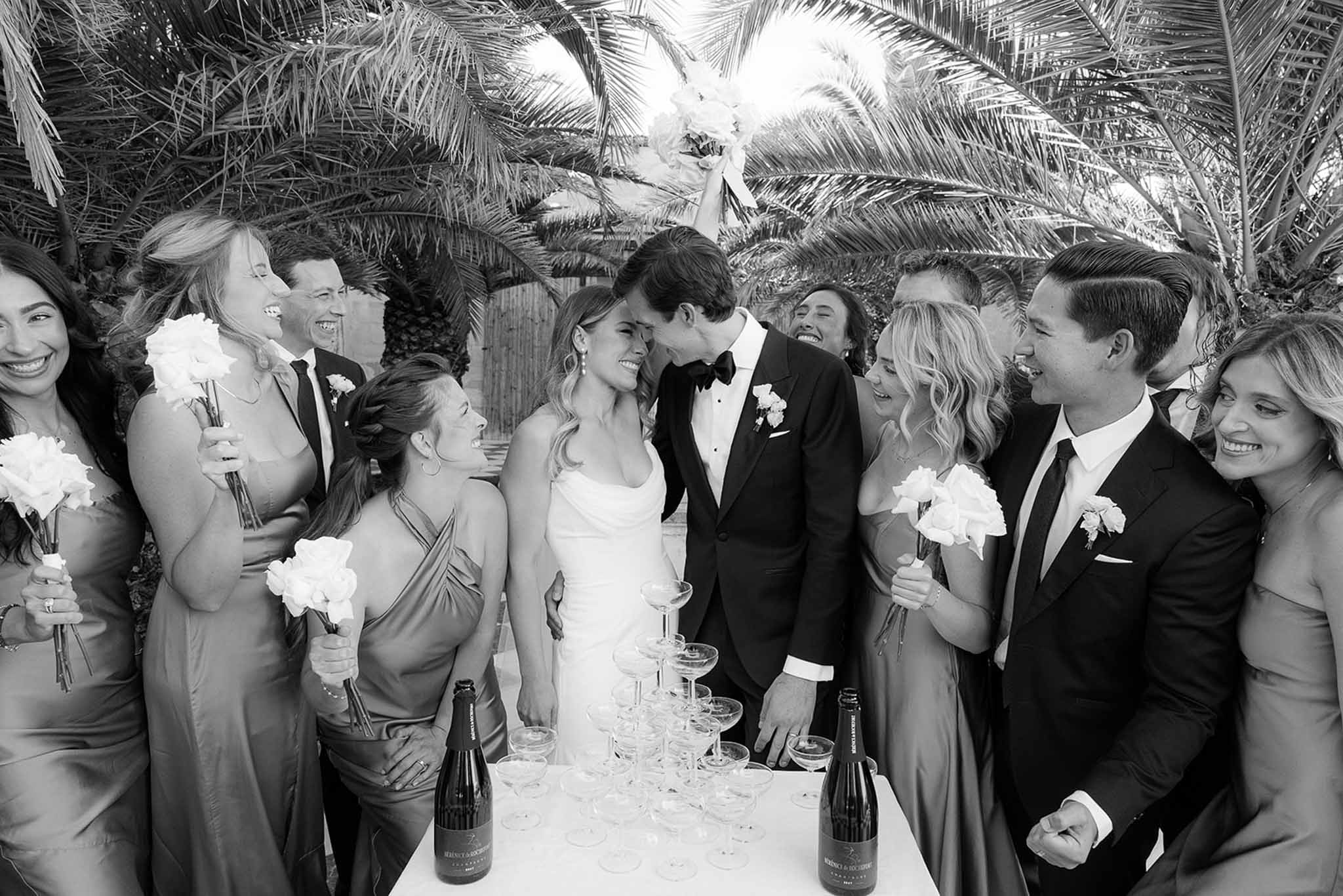 Wedding reception group portrait with bridal party and guests at outdoor tropical venue