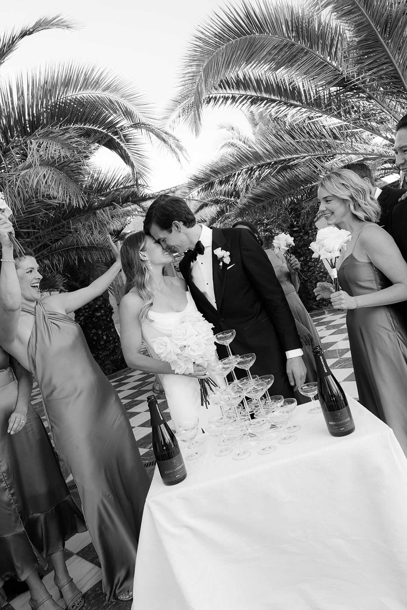 Wedding party gathering around champagne table during cocktail hour at tropical resort venue