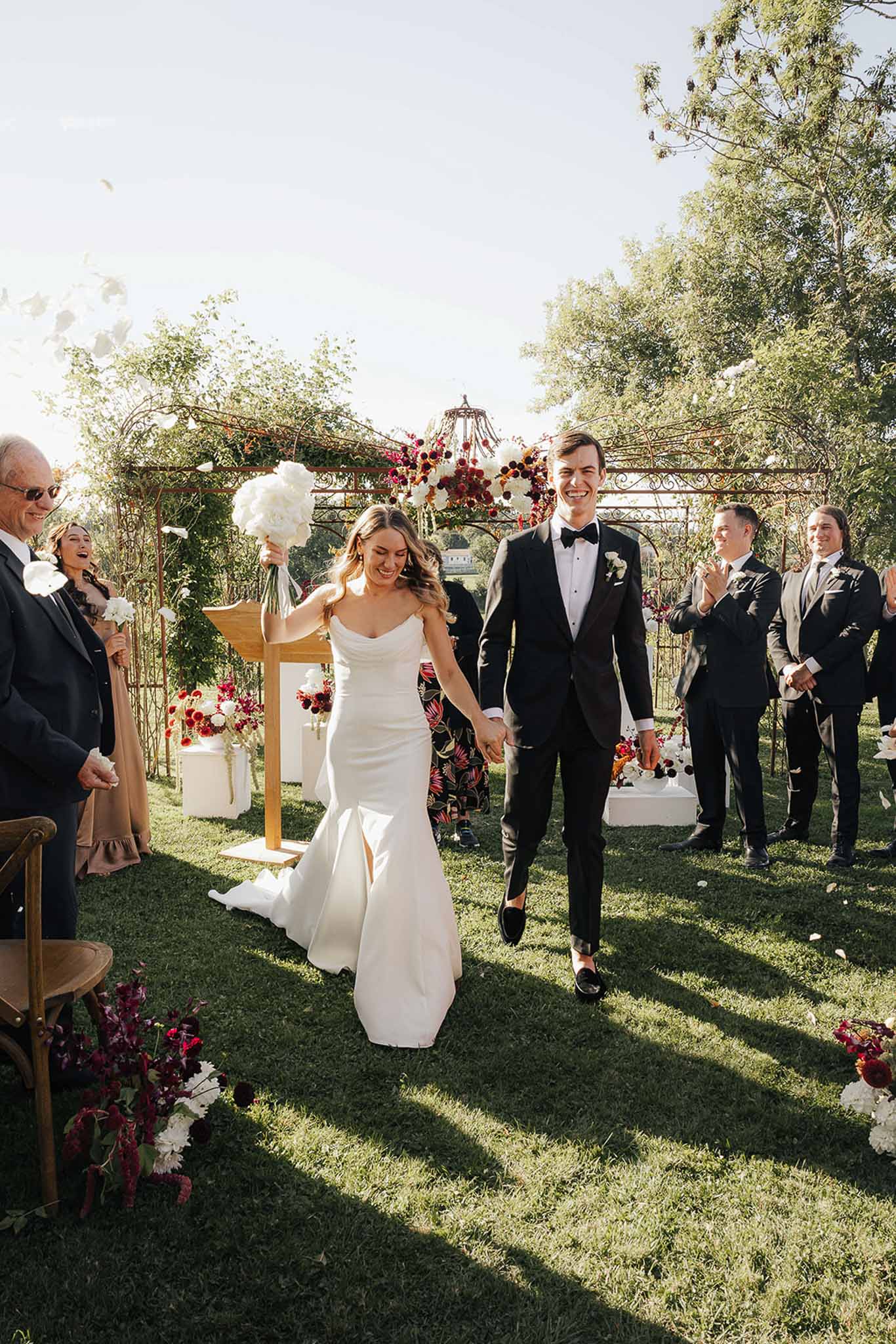 Bride and groom walking down aisle during recessional at outdoor garden ceremony