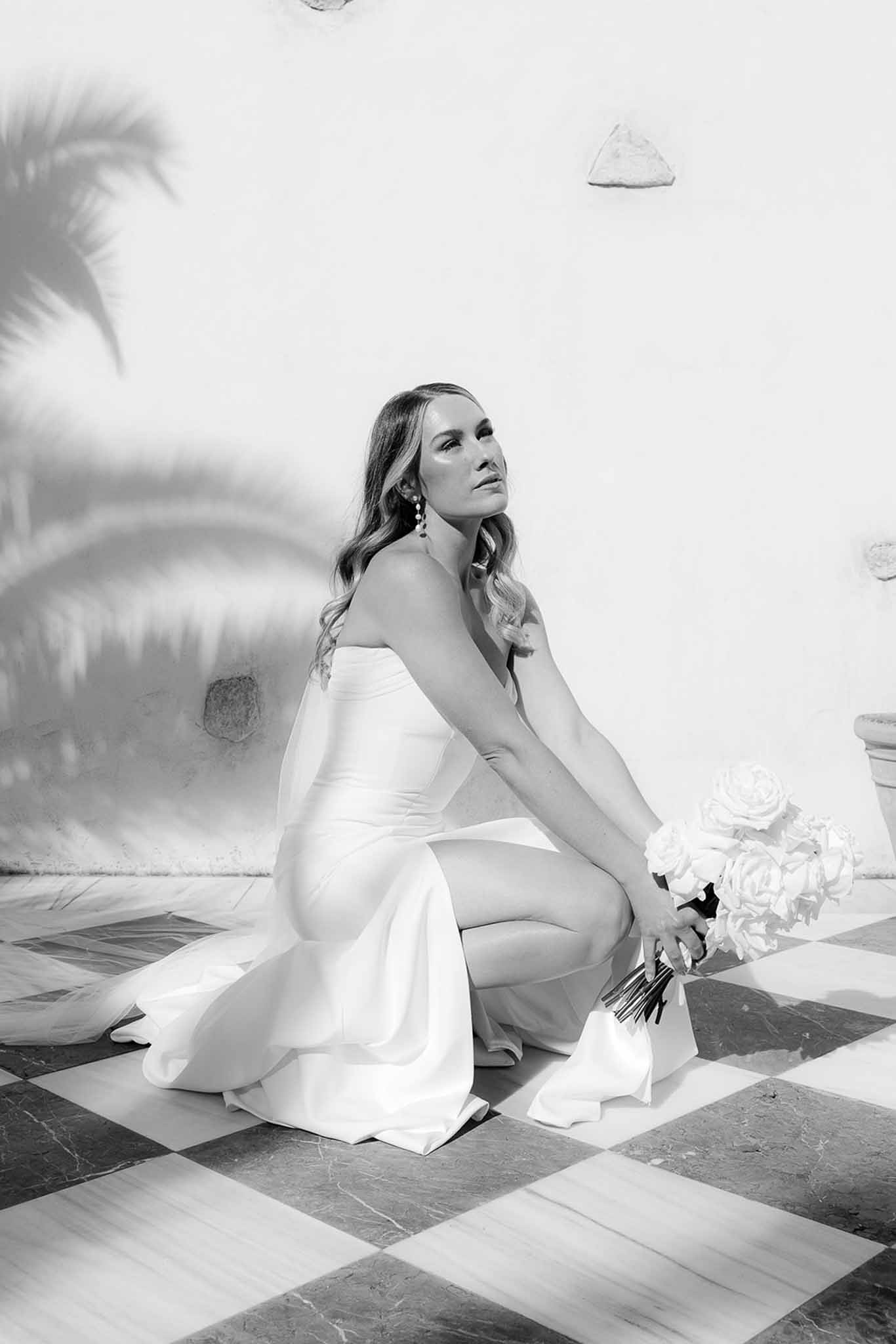Black and white bridal portrait of bride in strapless wedding dress holding bouquet on geometric tiled floor