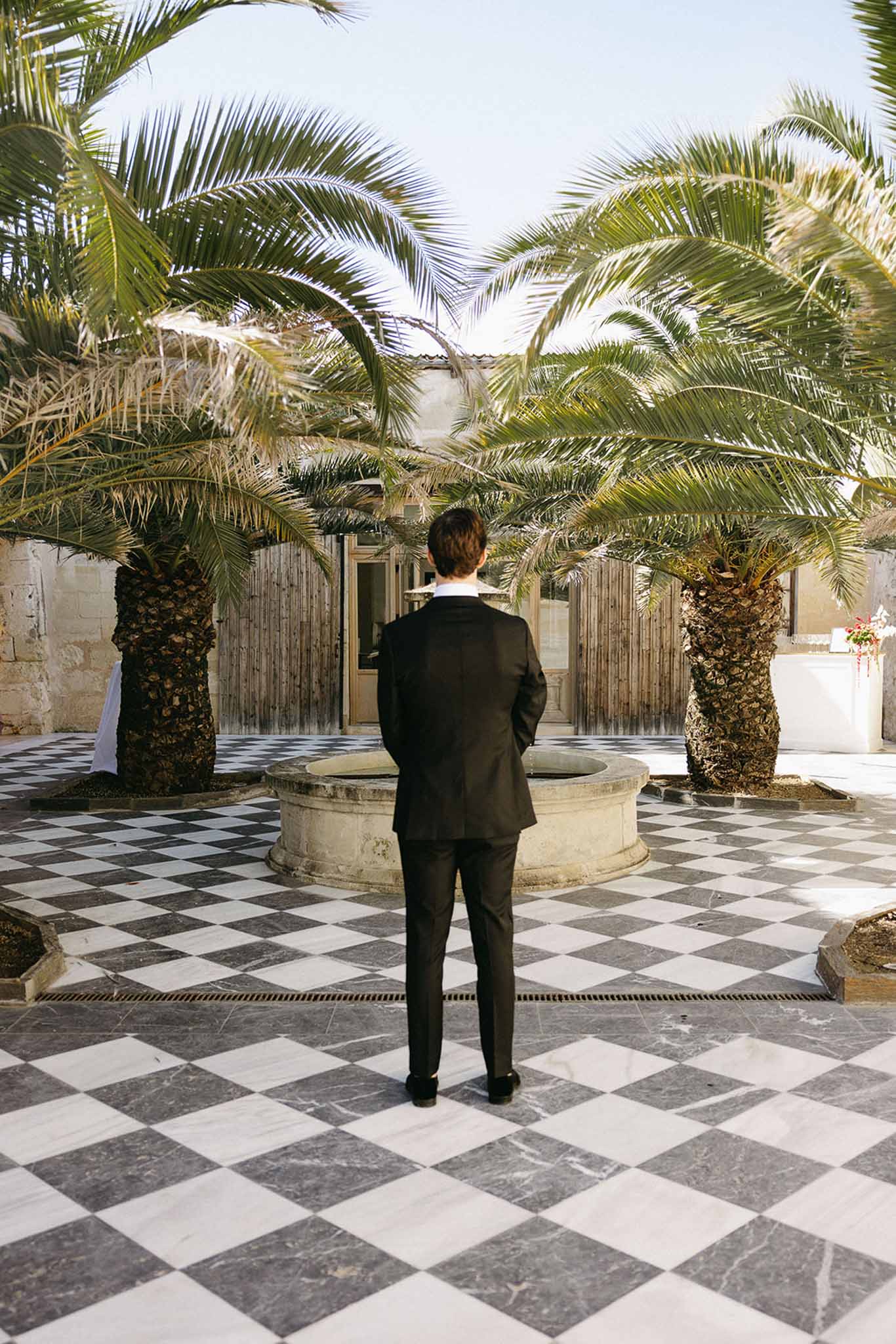 Groom waiting in Mediterranean courtyard before first look ceremony