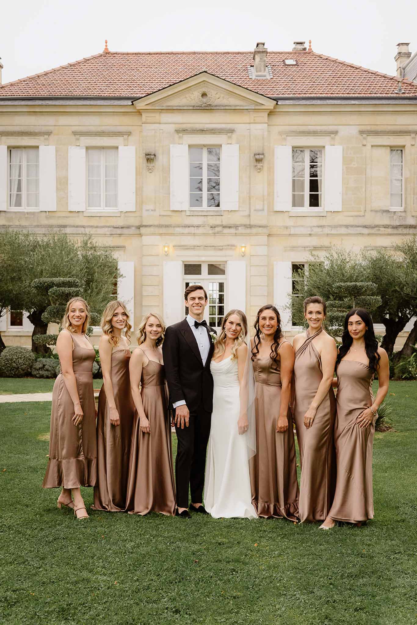Bridal party portrait with bridesmaids in taupe dresses at limestone manor house