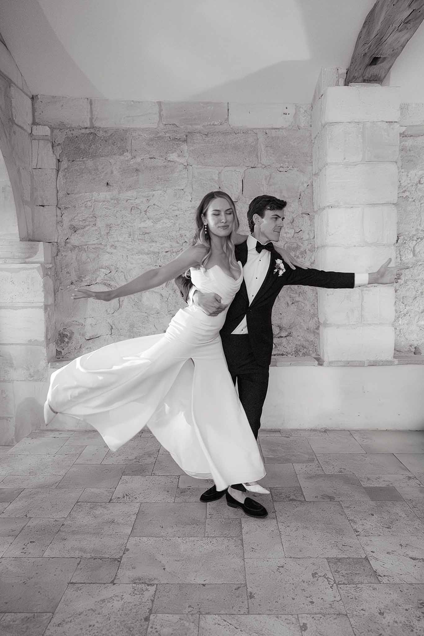 Bride and groom posing together in stone courtyard with classical architecture