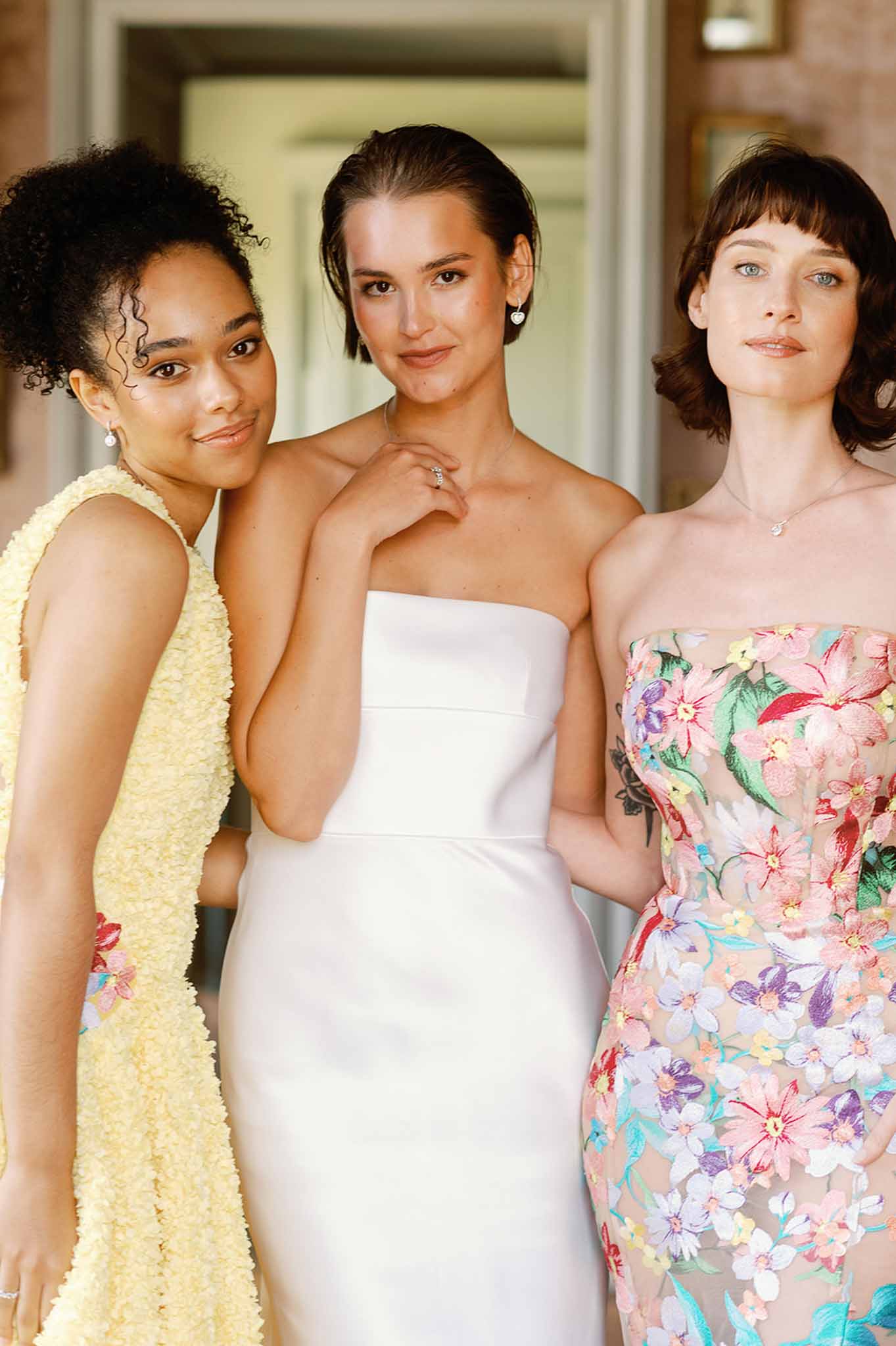 Bride and two bridesmaids portrait indoors with neutral walls and doorways in background