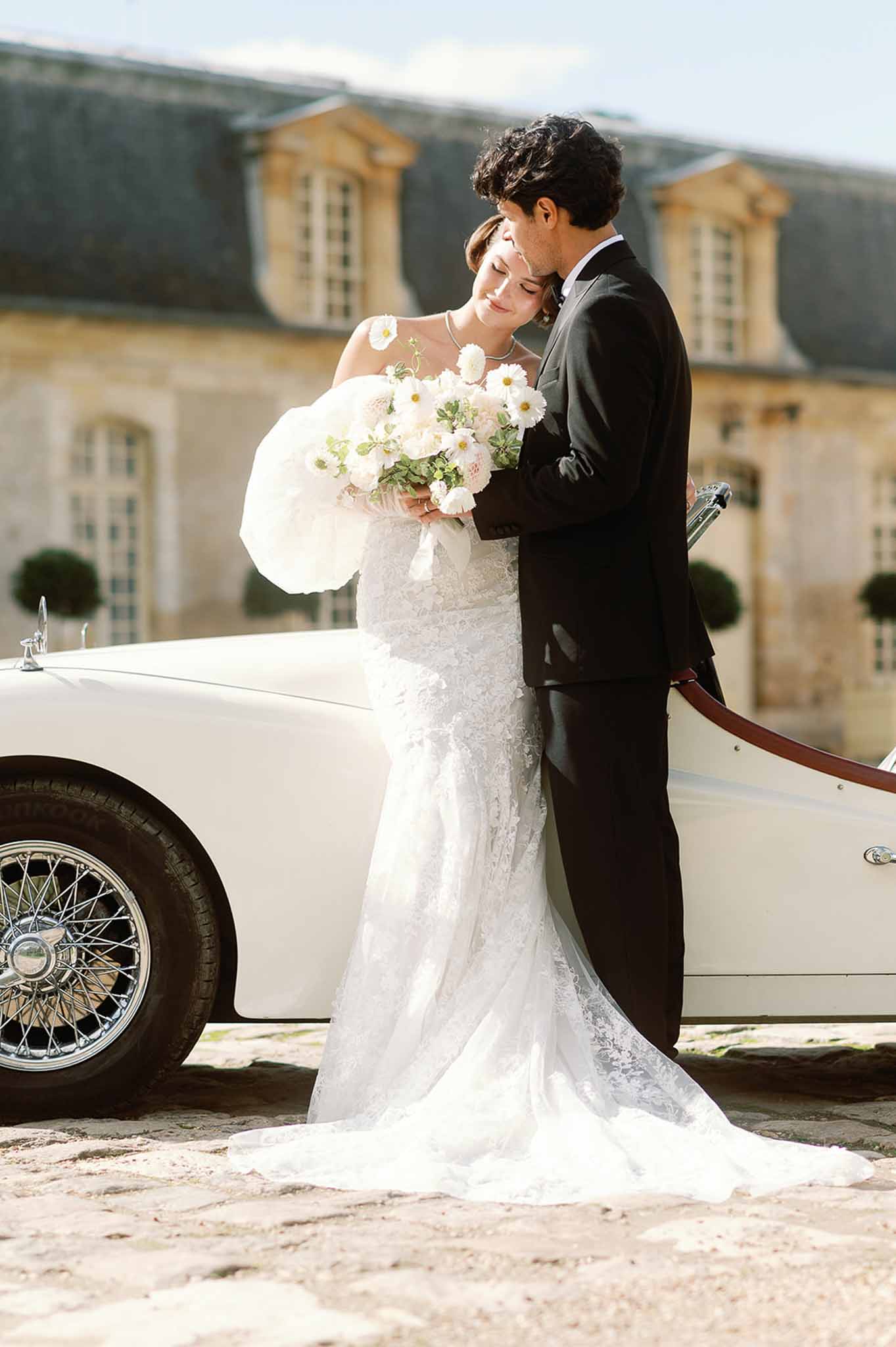 Bride and groom portrait with vintage car at stone manor house courtyard