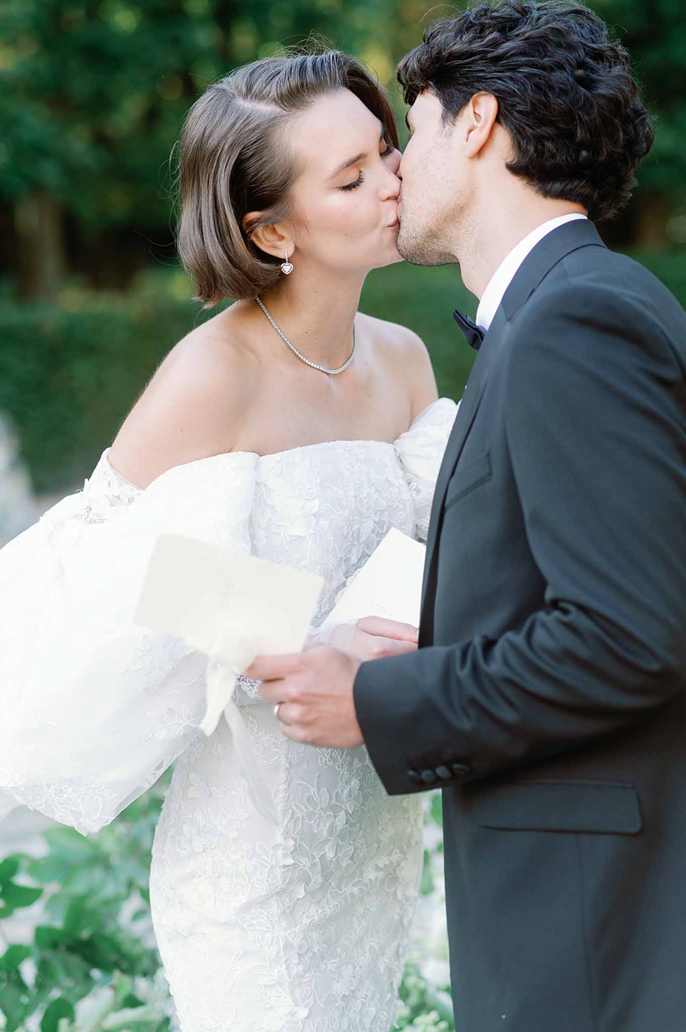 Bride and groom sharing first kiss in garden setting at outdoor wedding ceremony