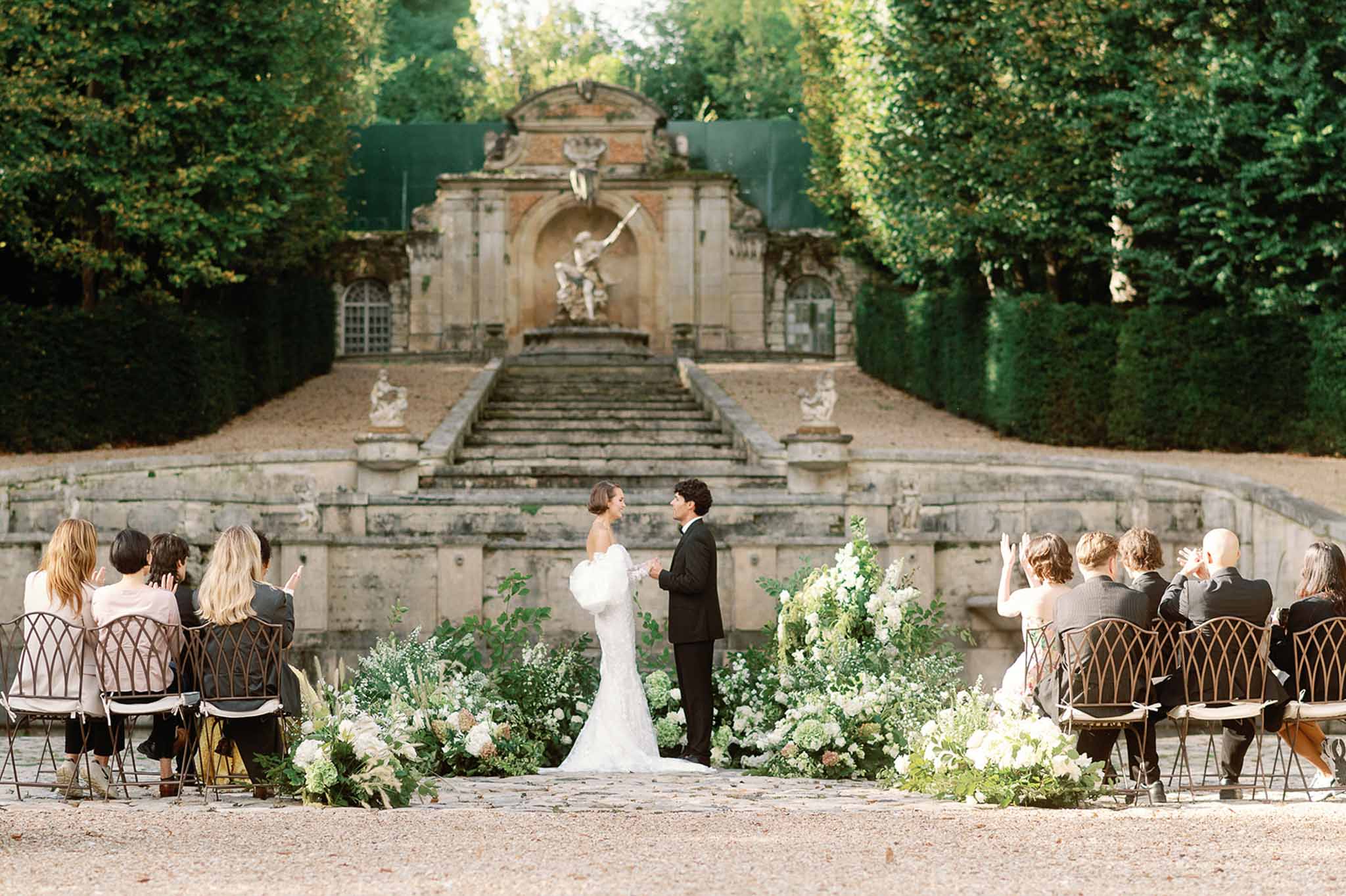 Wedding ceremony in formal garden courtyard with stone fountain and hedge landscaping