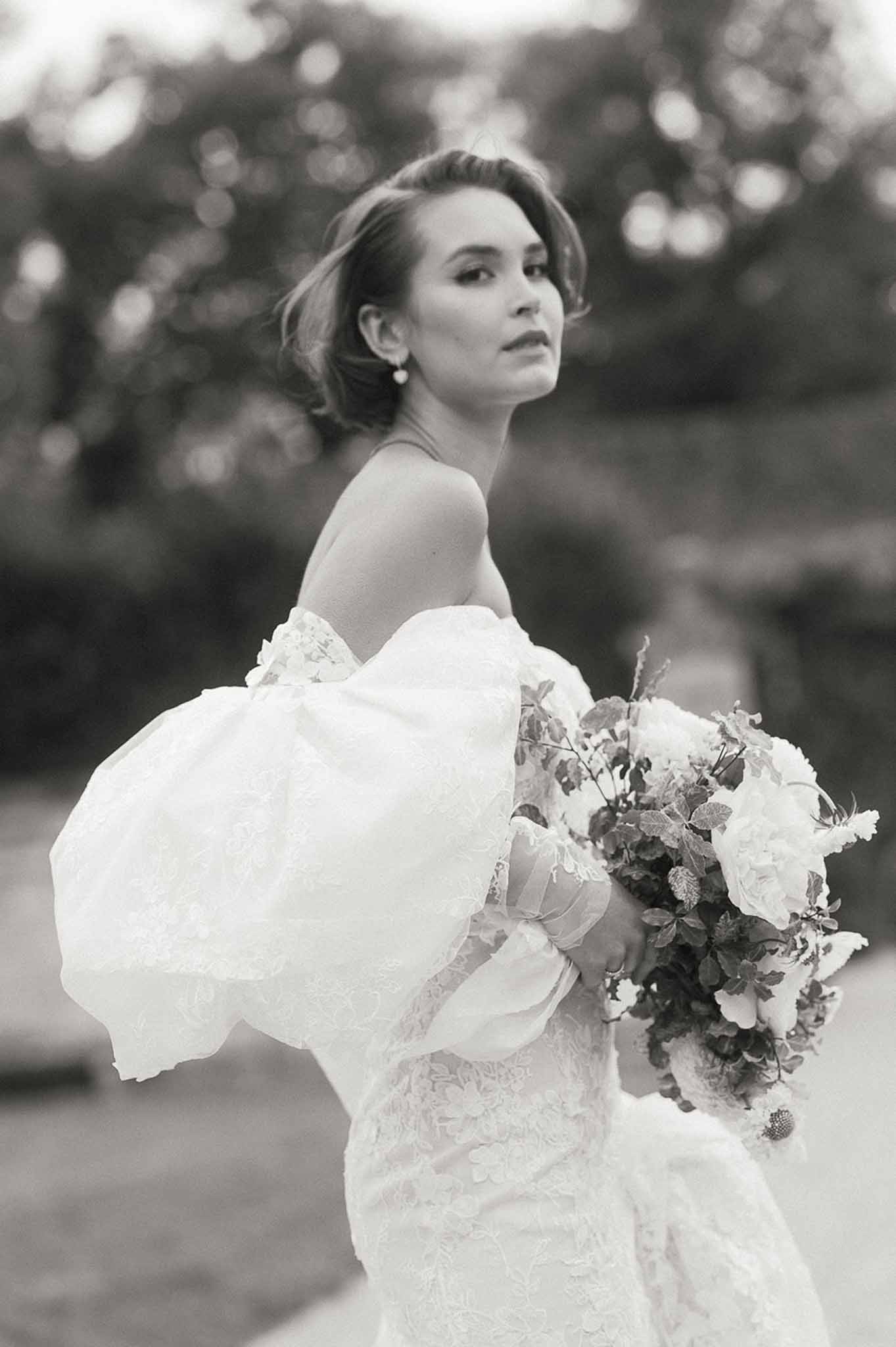 Black and white bridal portrait of bride in lace wedding dress in garden setting