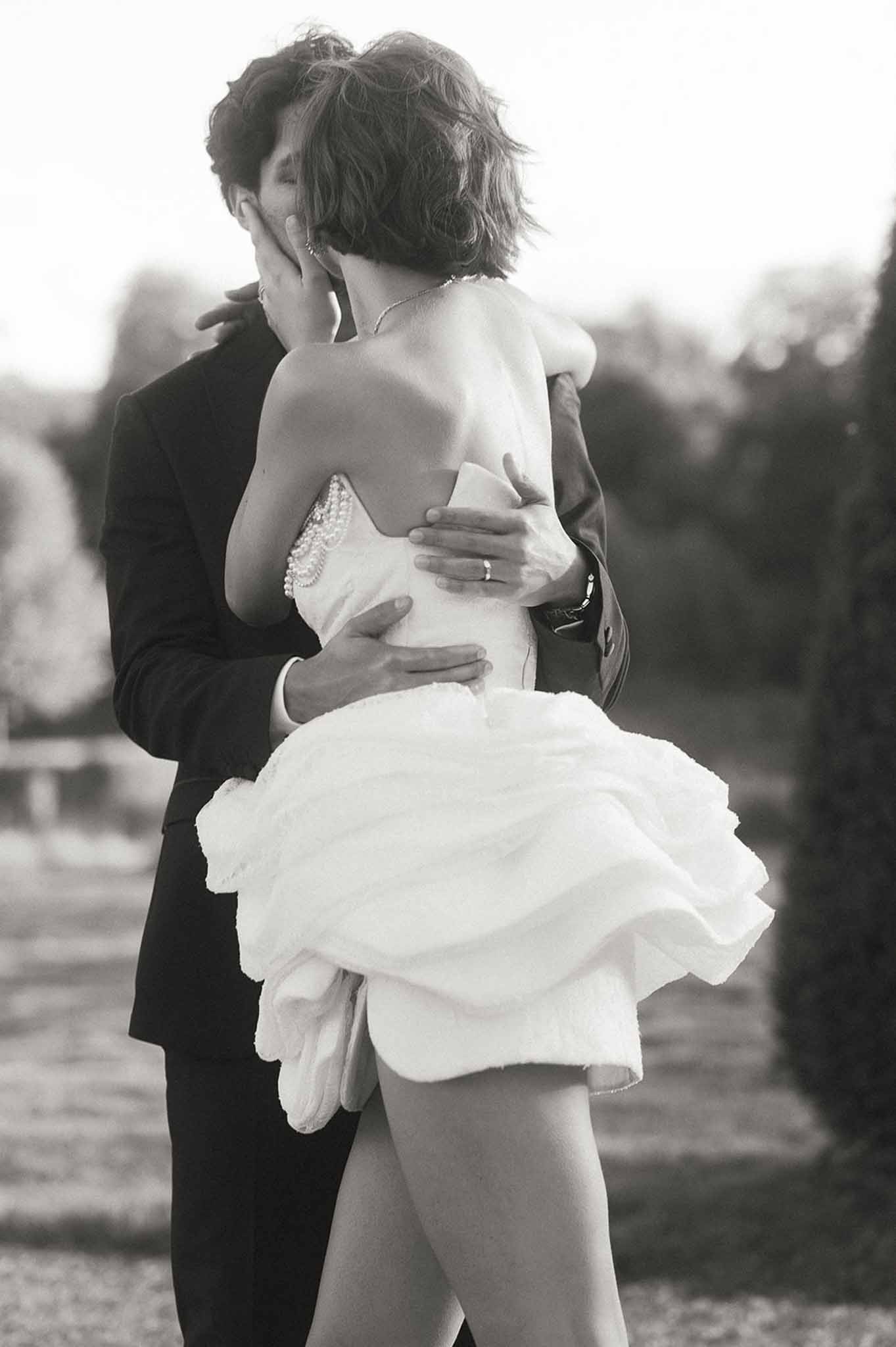 Black and white intimate portrait of bride and groom embracing outdoors in wedding attire