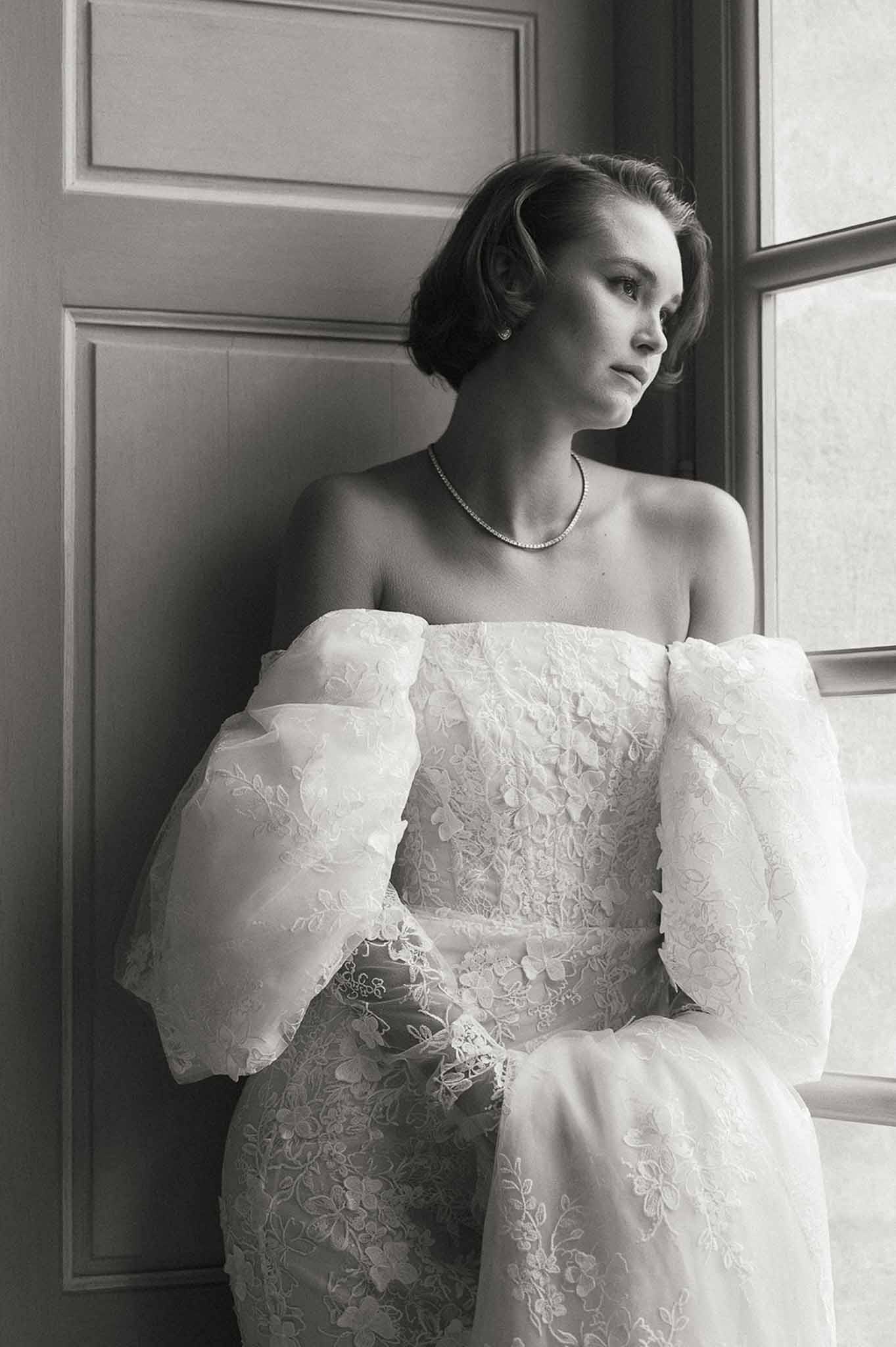 Bride in lace wedding gown with pearl accessories in elegant indoor portrait