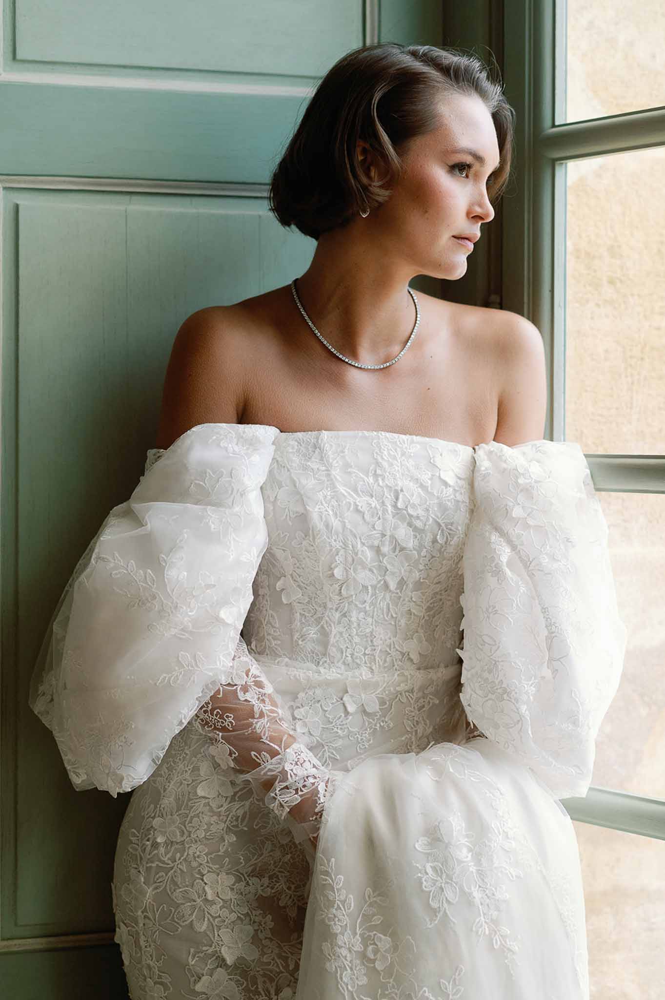 Bride in ivory lace wedding dress with diamond necklace in sage green paneled room