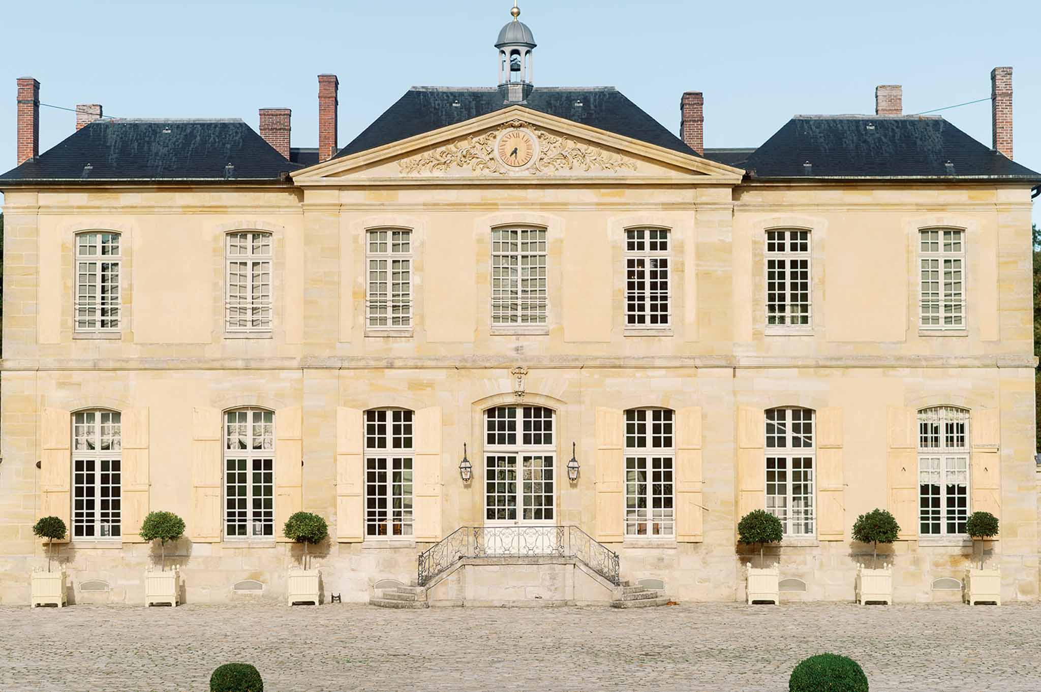 18th-century French château exterior with formal courtyard and topiary gardens