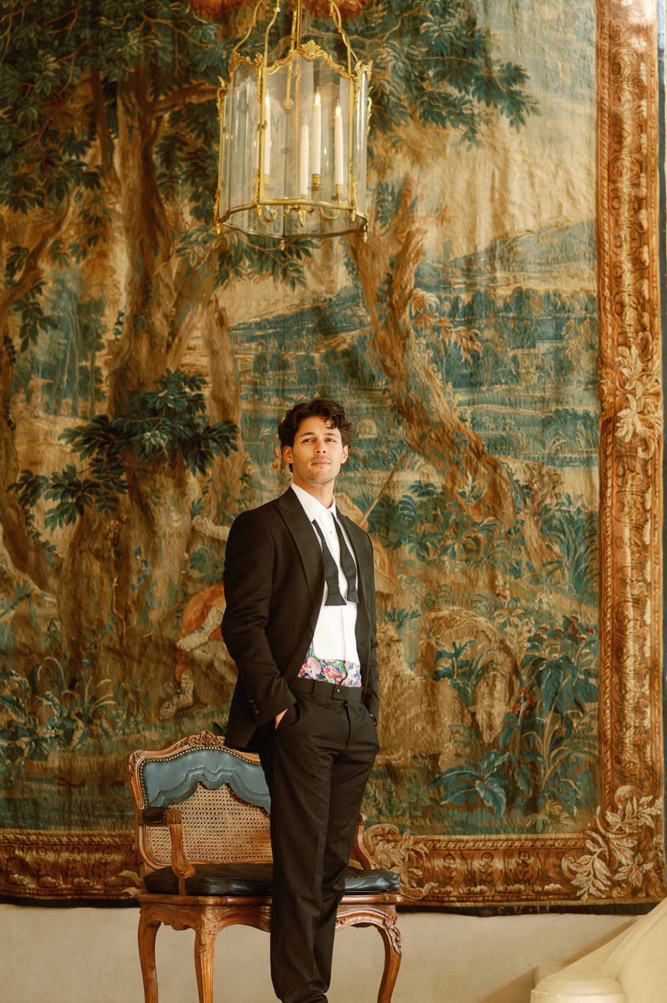 Groom portrait in ornate classical interior with tapestry wall and antique furnishings