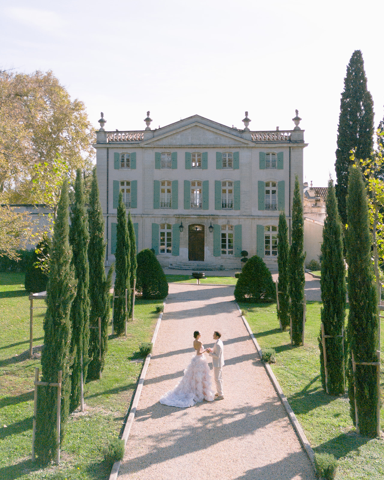 Bride and groom standing on cypress-lined pathway at neoclassical Italian villa