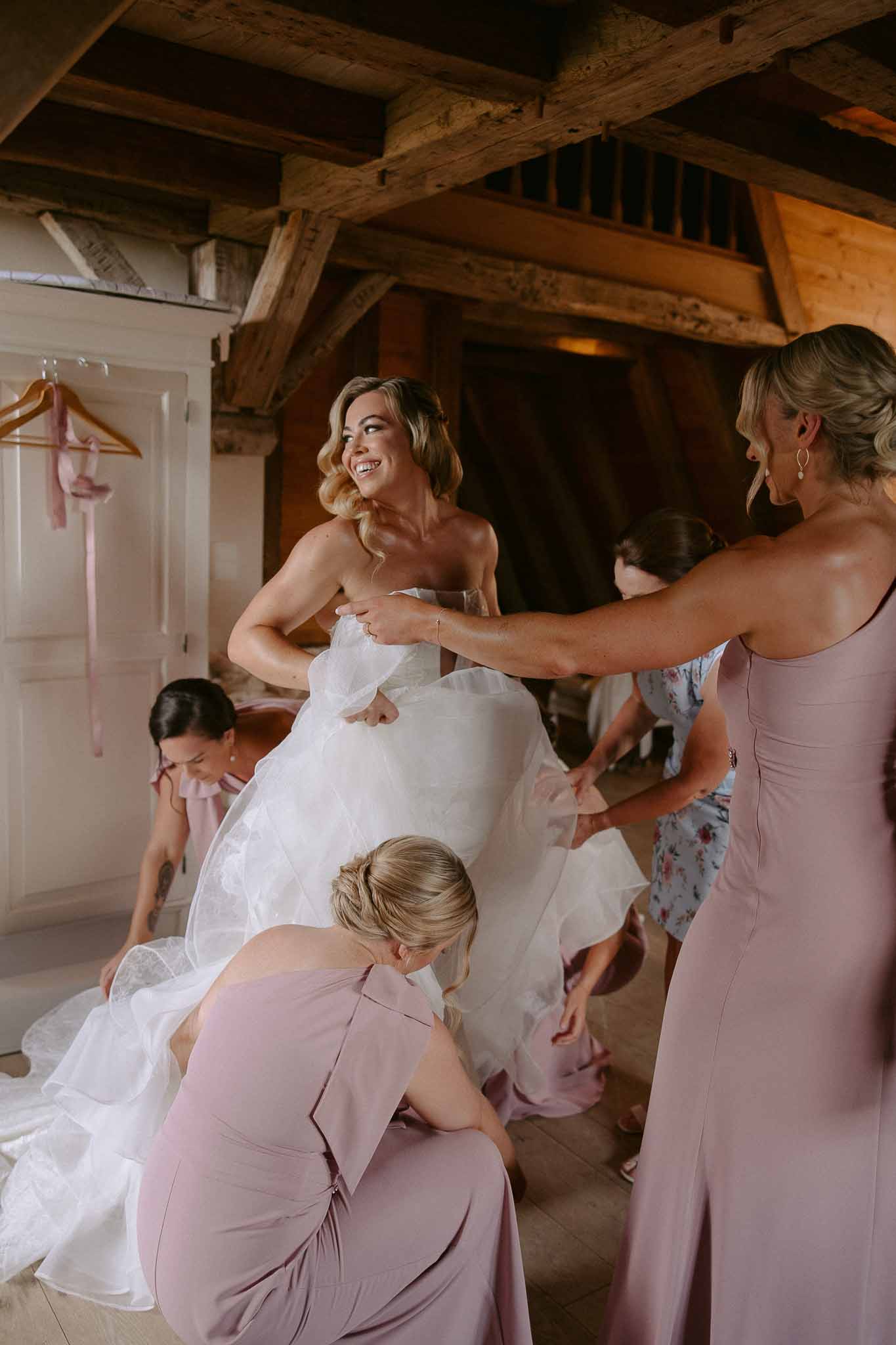 Bride getting ready with bridal party in rustic wooden venue with exposed beams