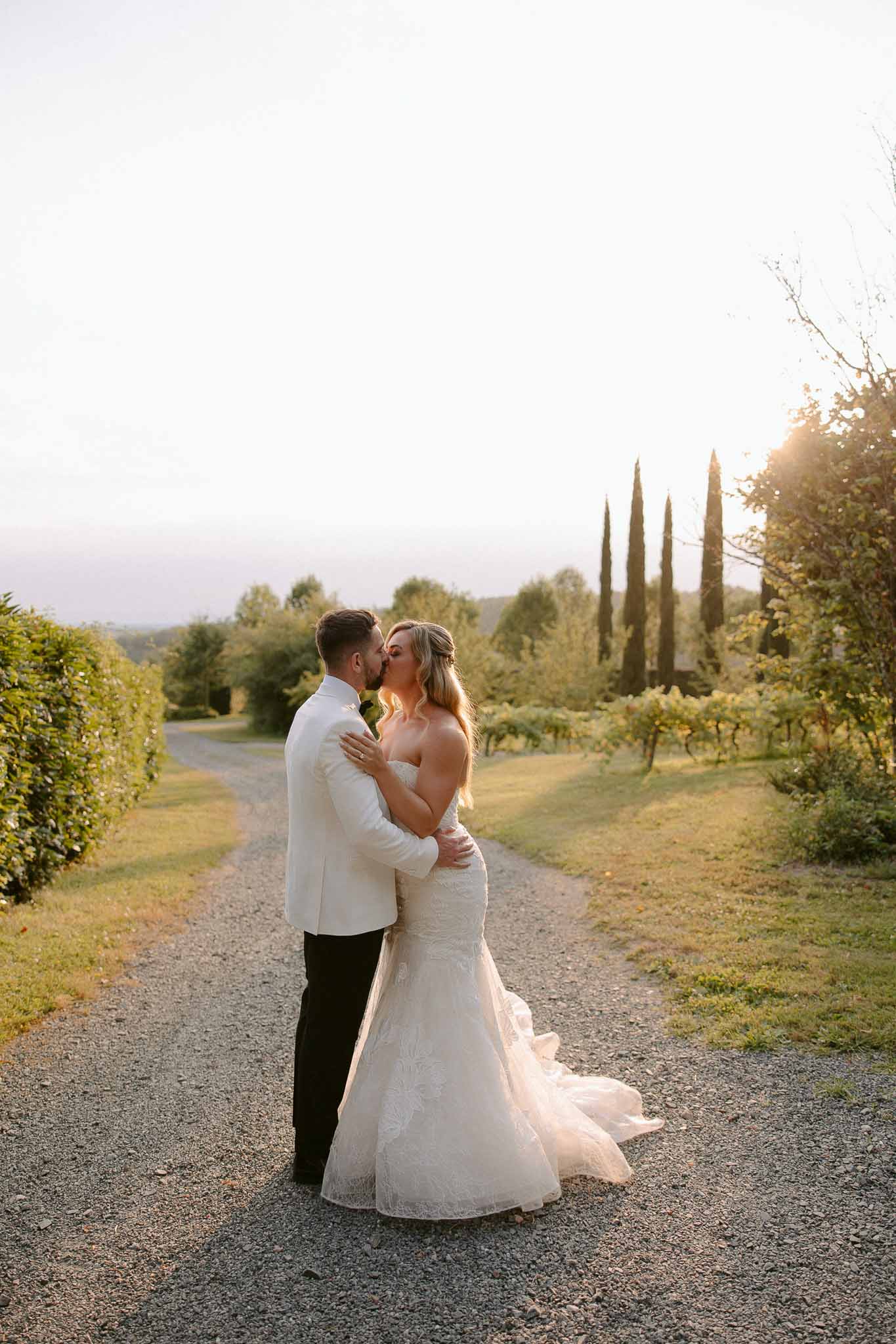 Bride and groom kissing on gravel driveway at Tuscan countryside wedding venue